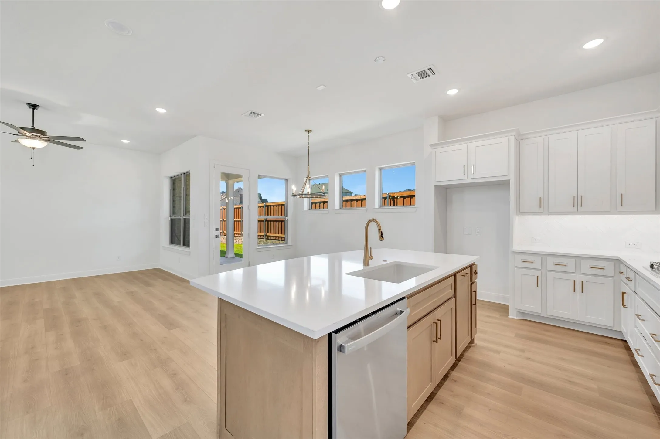 Bright kitchen with white cabinetry, a large center island, wood-finish flooring, recessed lighting, and ample natural light
