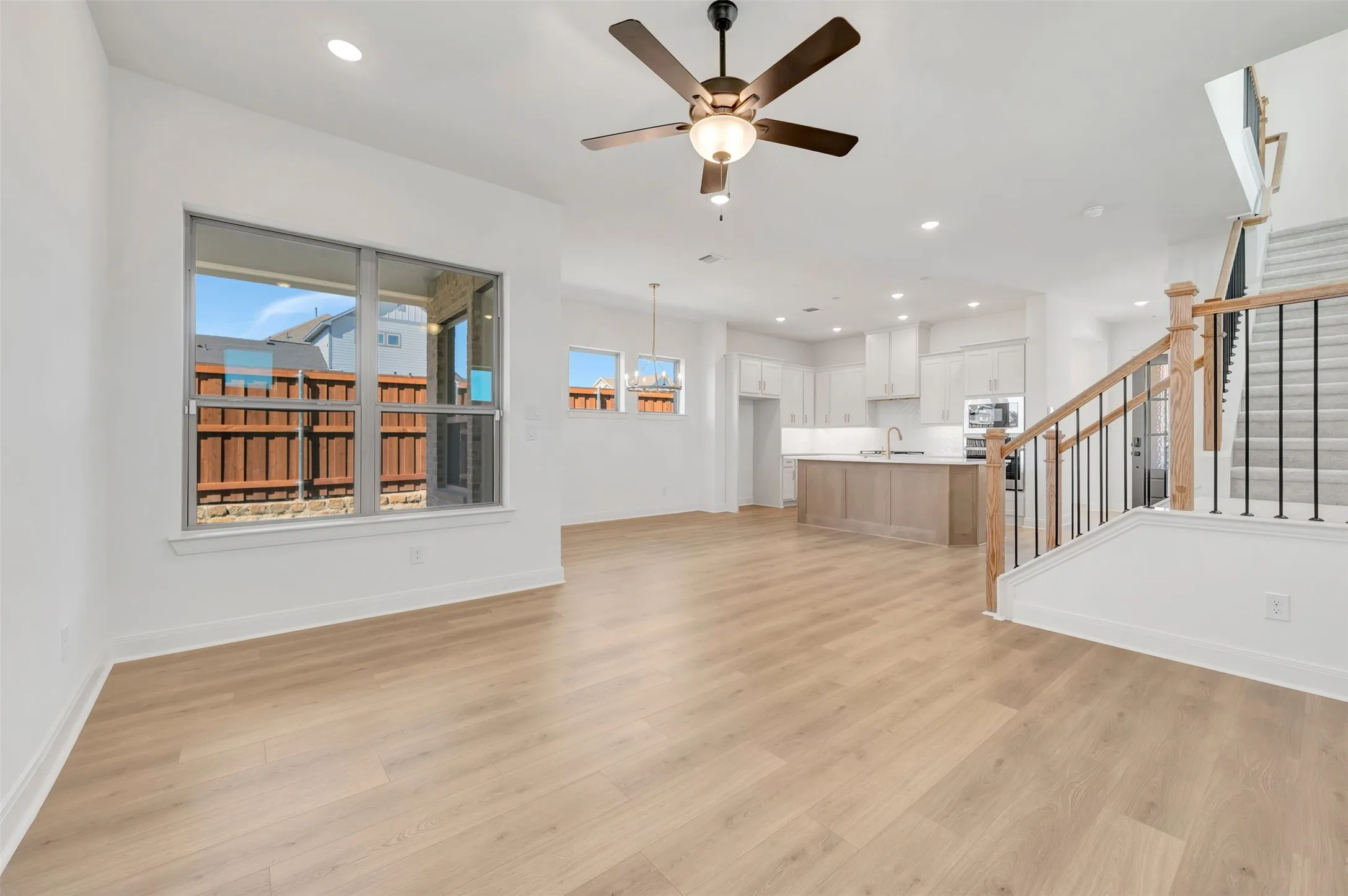Open-concept living space with wood-finish flooring, a contemporary ceiling fan, and recessed lighting