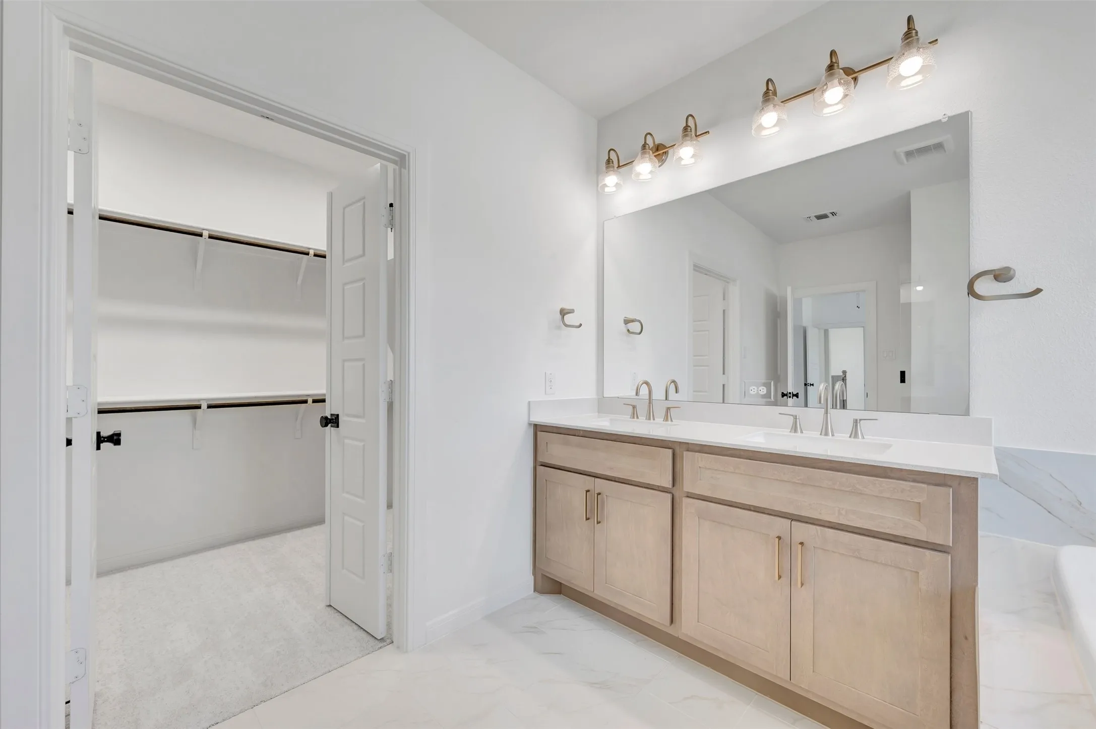 Dual vanity with light wood-finish cabinetry and white countertops, featuring two undermount sinks and brushed nickel faucets