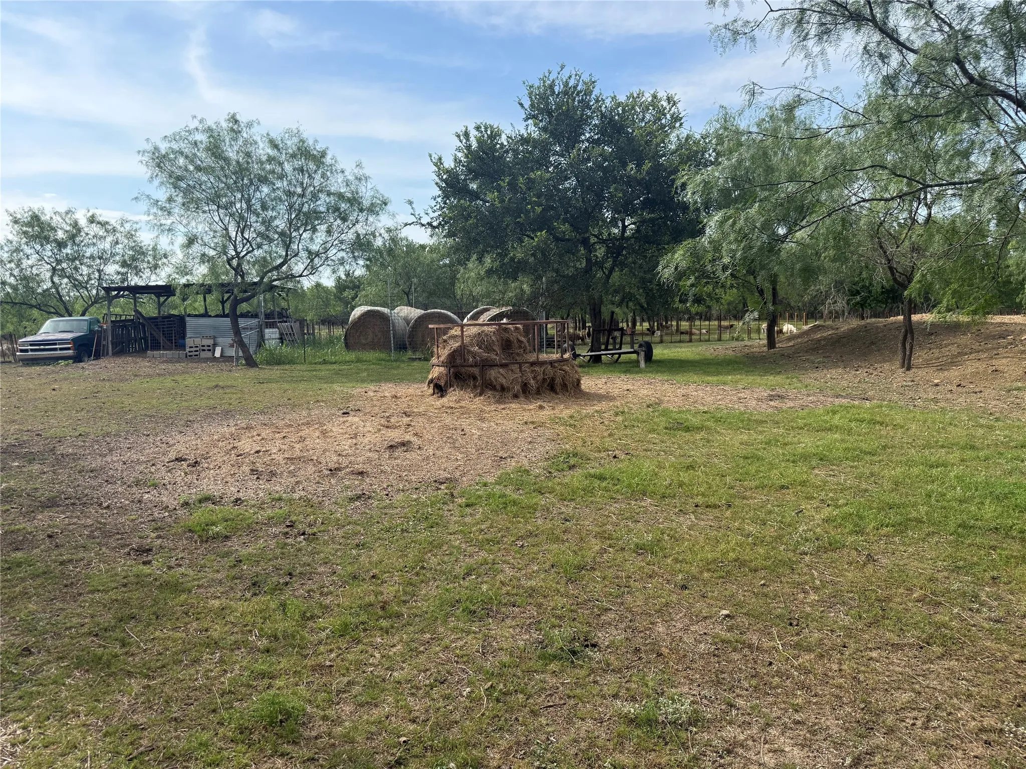 Expansive outdoor area featuring mature trees, partial fencing, and a barn structure