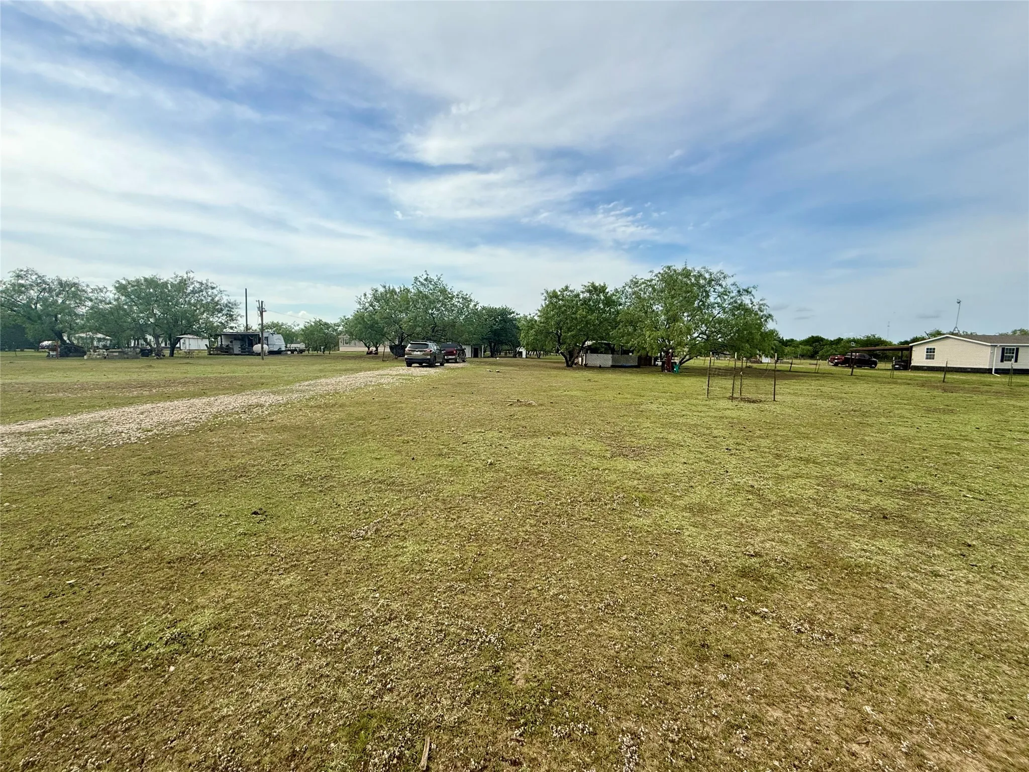Expansive open lot featuring a gravel pathway and mature trees