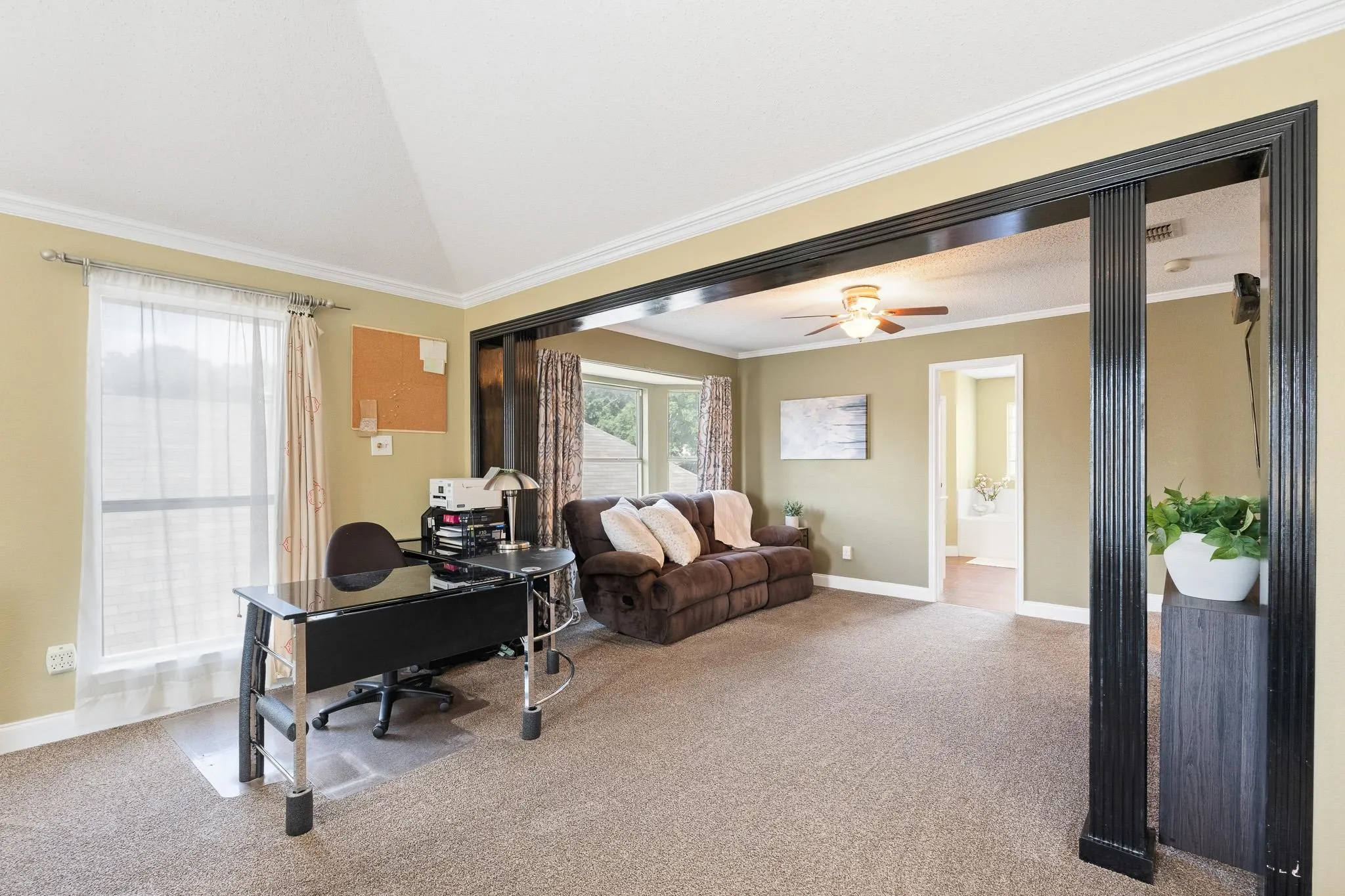 Sitting area inside primary bedroom featuring a vaulted ceiling, recessed lighting, and crown molding