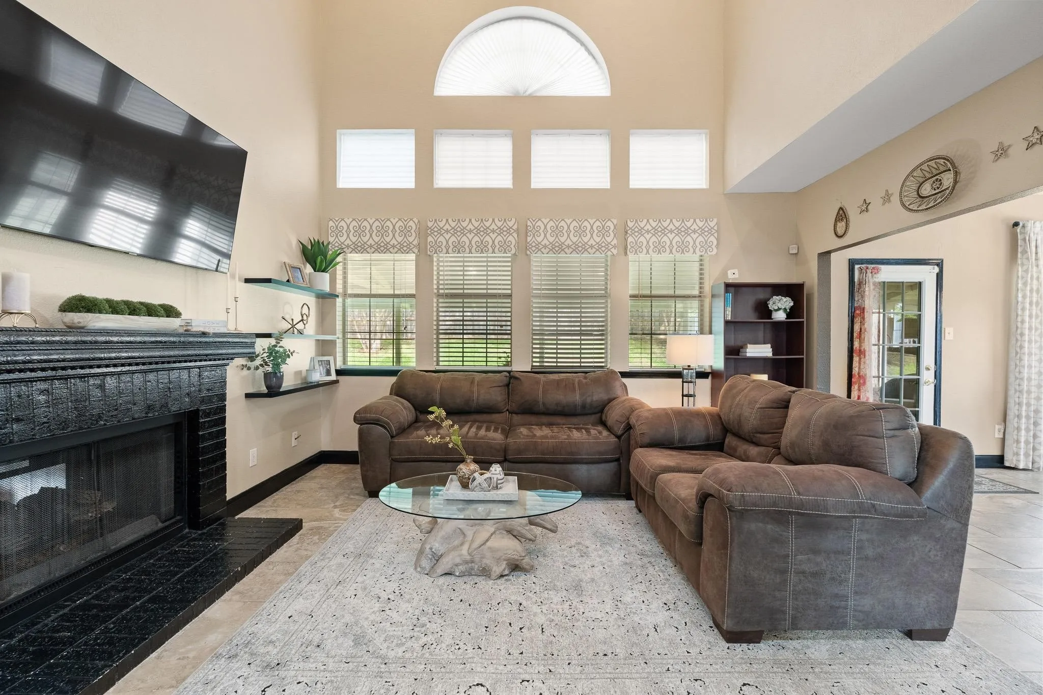 Living area featuring a black tile fireplace with an integrated mantel, vaulted ceilings, and a large arched window