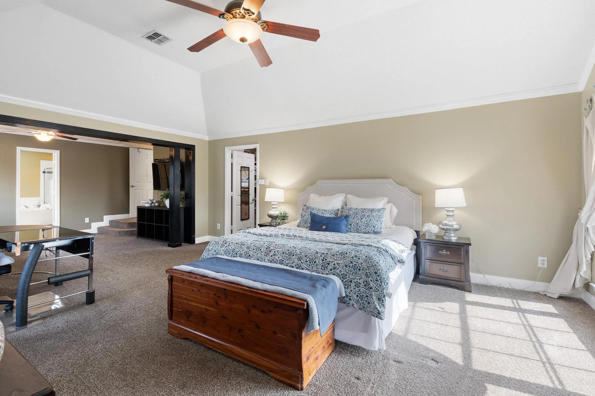 Vaulted ceiling bedroom featuring a ceiling fan, crown molding, and carpeted flooring