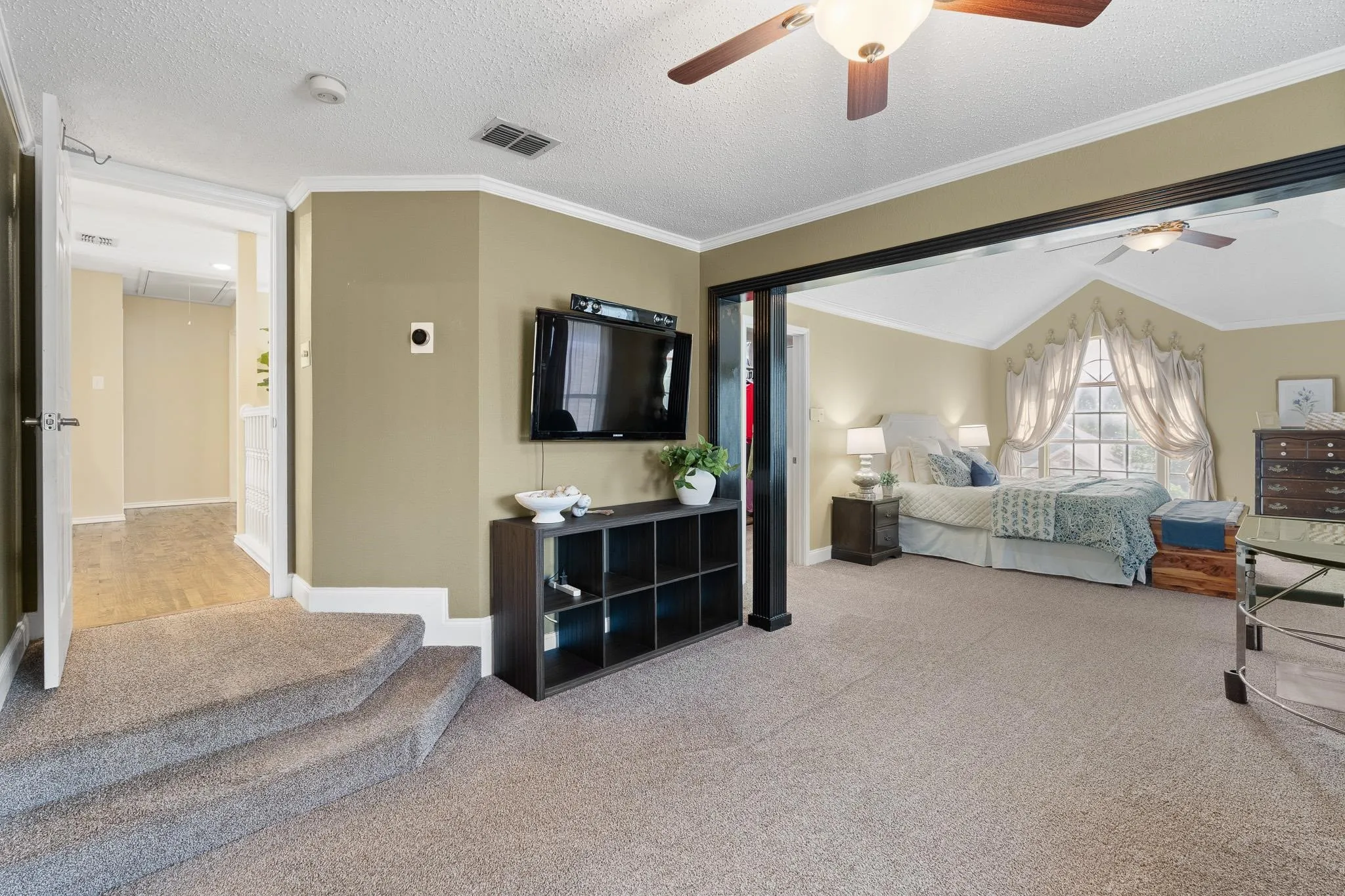 Primary bedroom retreat with a stepped entrance, featuring a wood-finish ceiling fan and sitting area