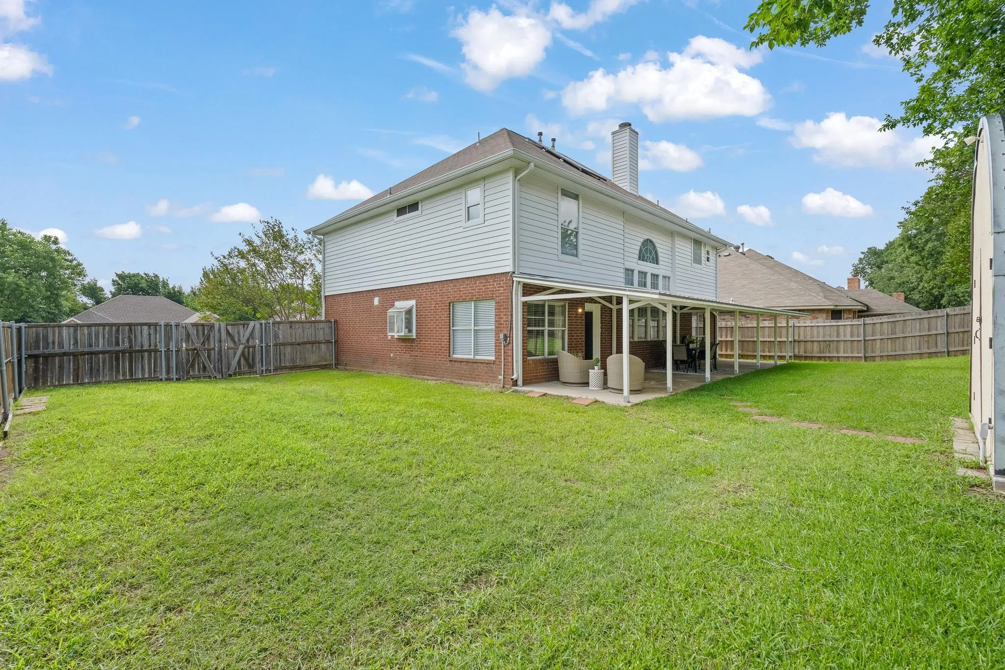 Expansive backyard featuring a covered patio, a full privacy fence, and a spacious lawn