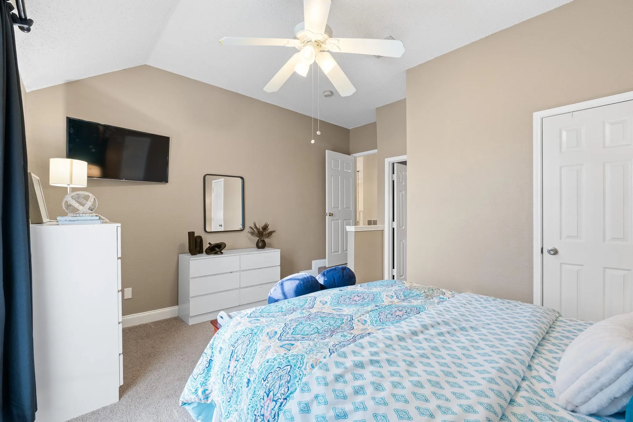 Vaulted ceiling with a ceiling fan, neutral wall tones, and carpeted flooring