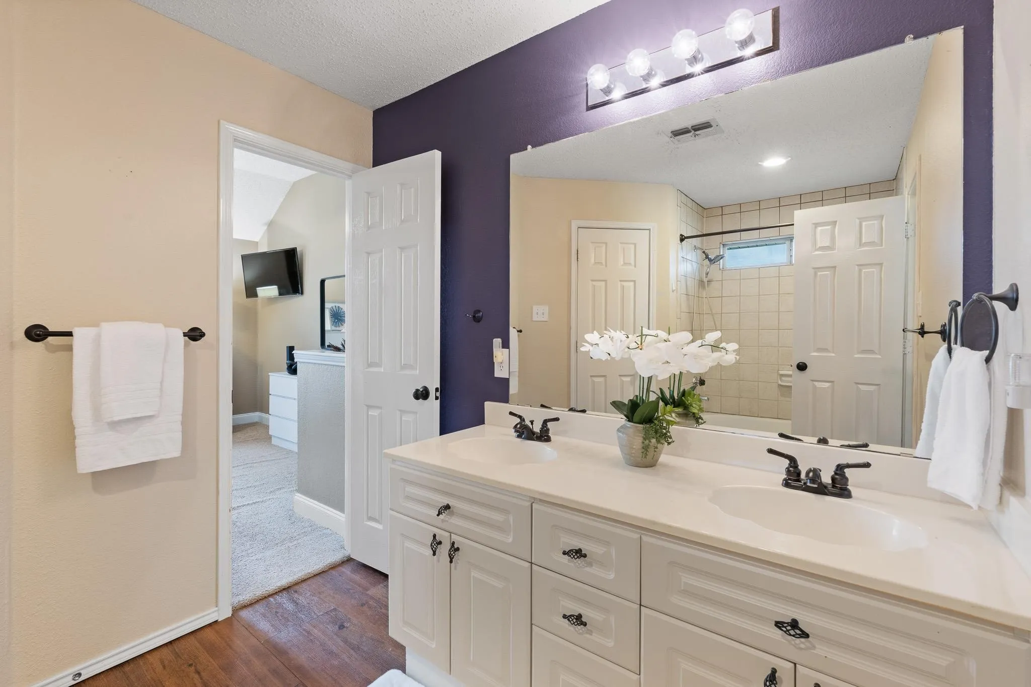 Jack-and-Jill bathroom featuring a dual vanity with white cabinetry, integrated sinks, and black hardware