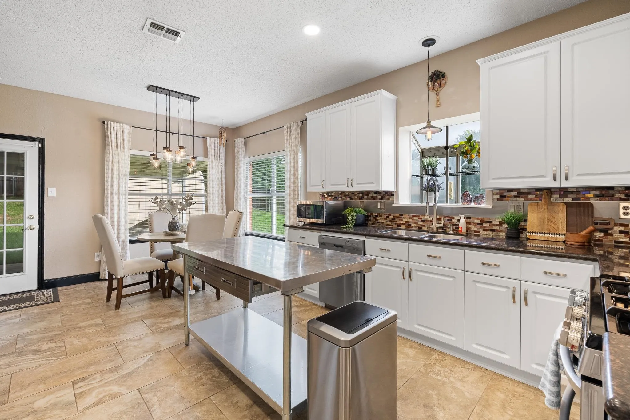 Kitchen featuring white cabinetry, dark countertops, a mosaic tile backsplash, and tile flooring