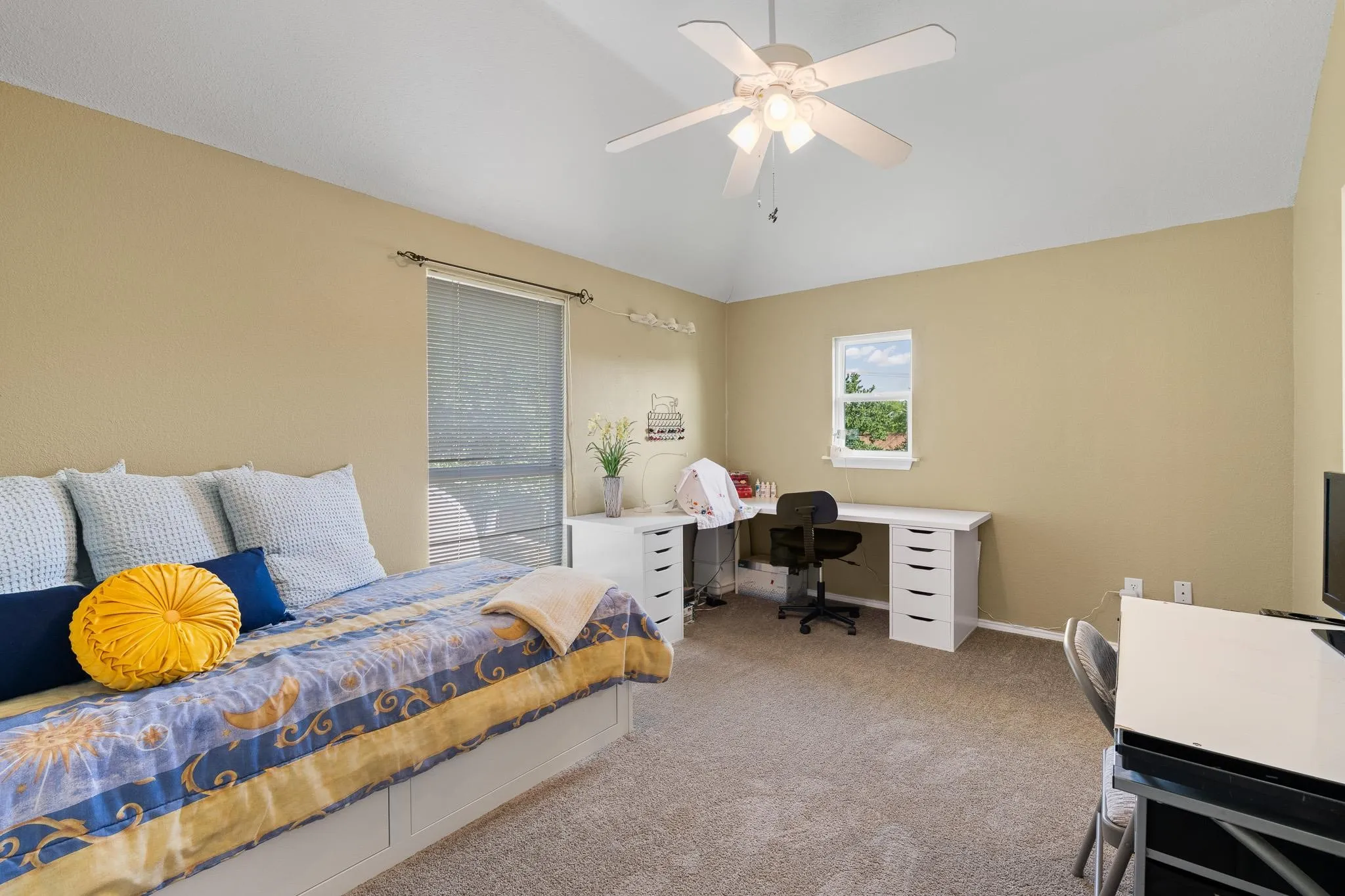 Carpeted interior room with neutral-toned walls, a vaulted ceiling, and a ceiling fan with light fixture