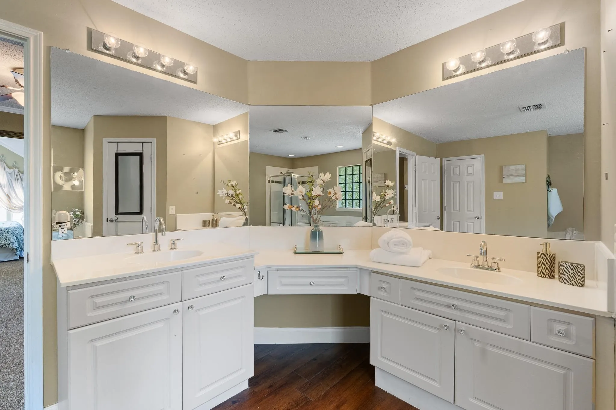 Bathroom featuring dual white vanities with integrated sinks, white countertops, and wood-finish flooring