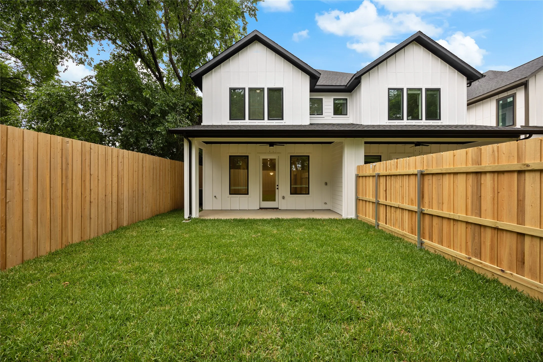 Backyard featuring a covered patio, manicured lawn, and new wood fencing