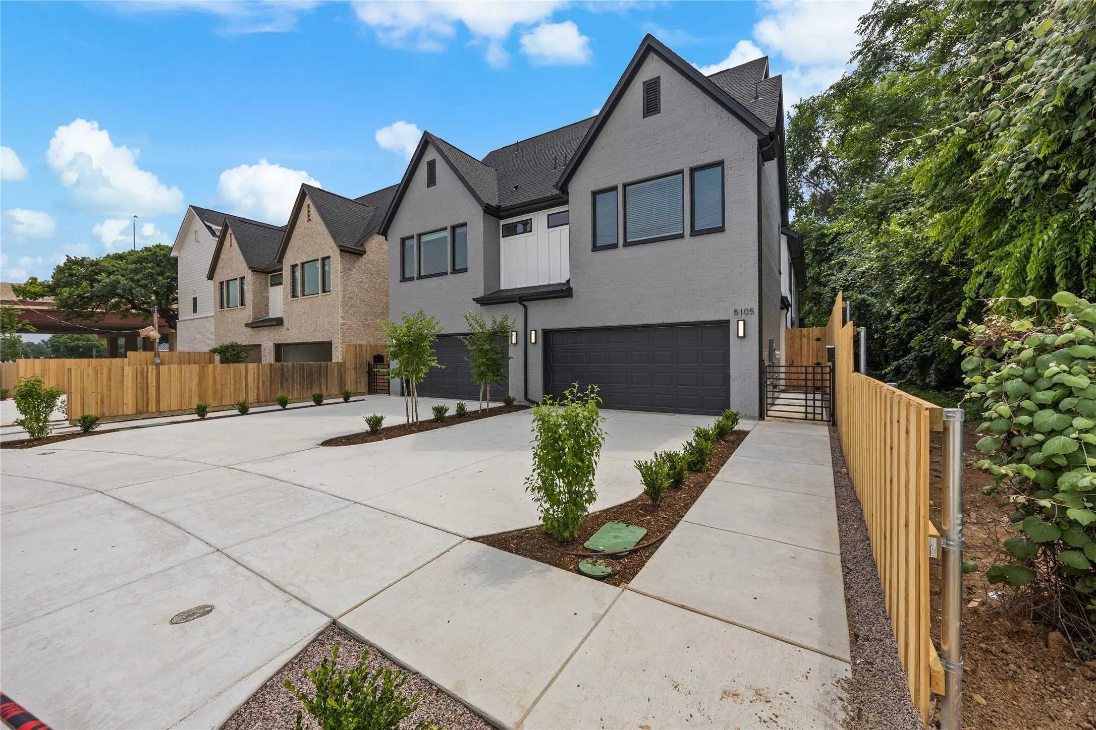 Modern townhome exterior featuring a gray brick facade, dark roofing, and black frame windows