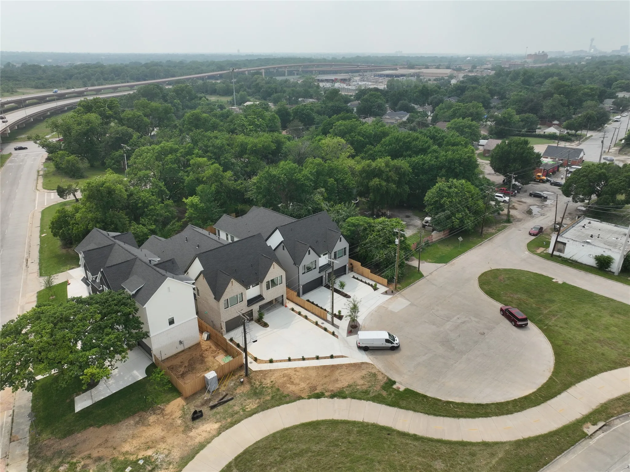 Aerial perspective showcasing a collection of contemporary residences featuring varied exterior finishes, dark shingle roofing, and concrete driveways