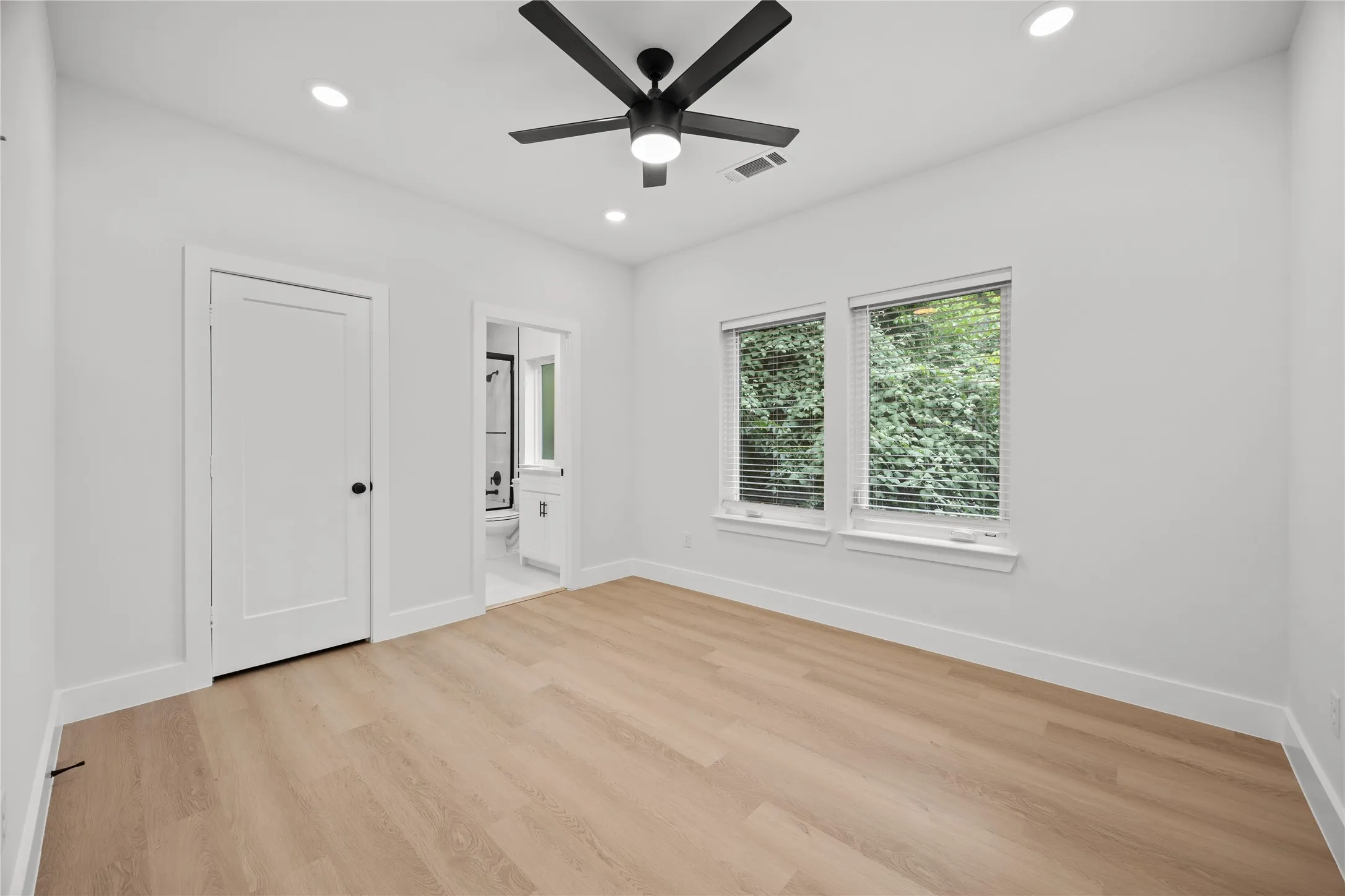 Bright interior room featuring light wood-finish flooring, recessed lighting, and a contemporary ceiling fan