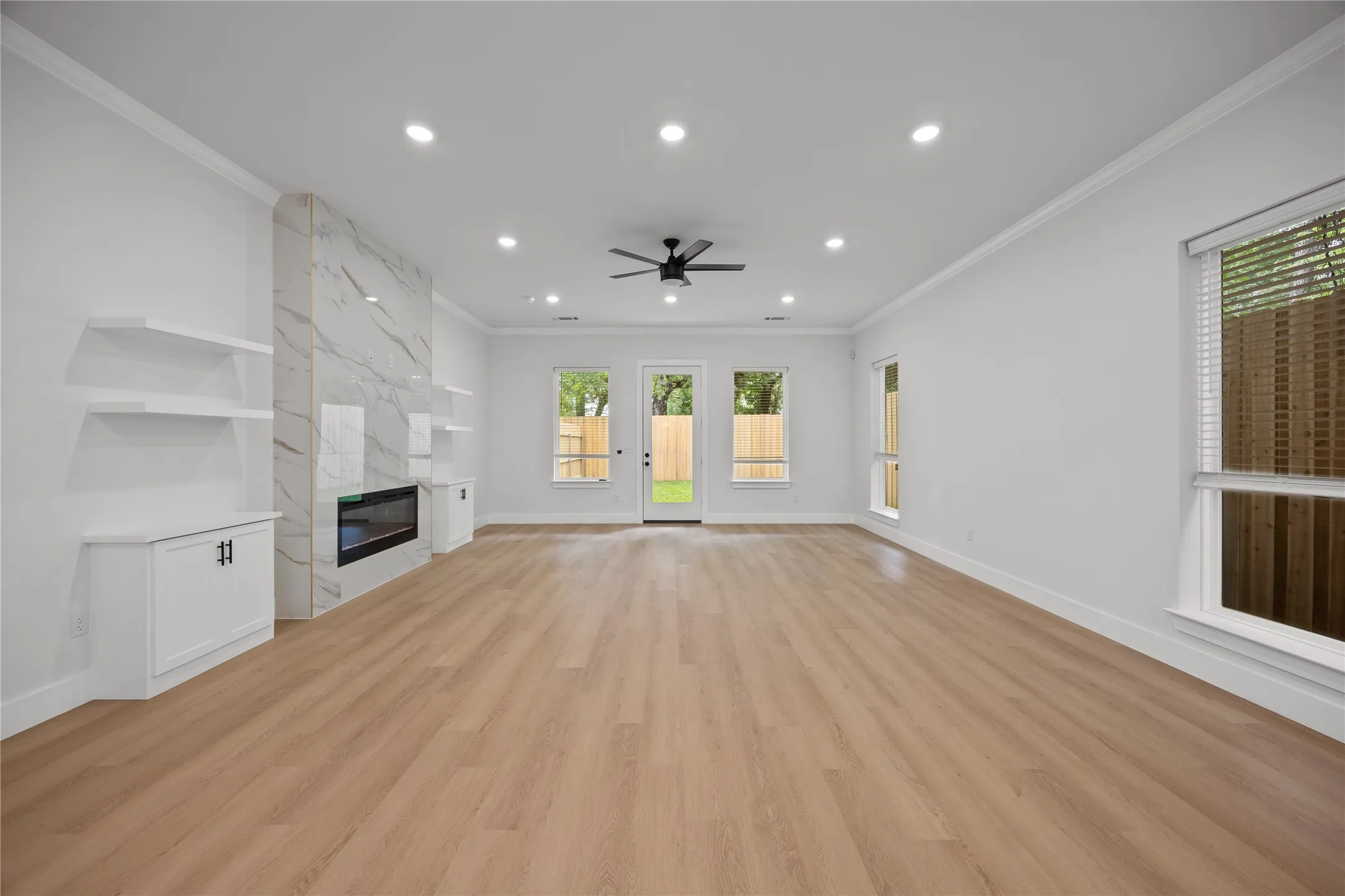 Spacious room with wood-finish flooring, recessed lighting, and a contemporary fireplace featuring a patterned surround