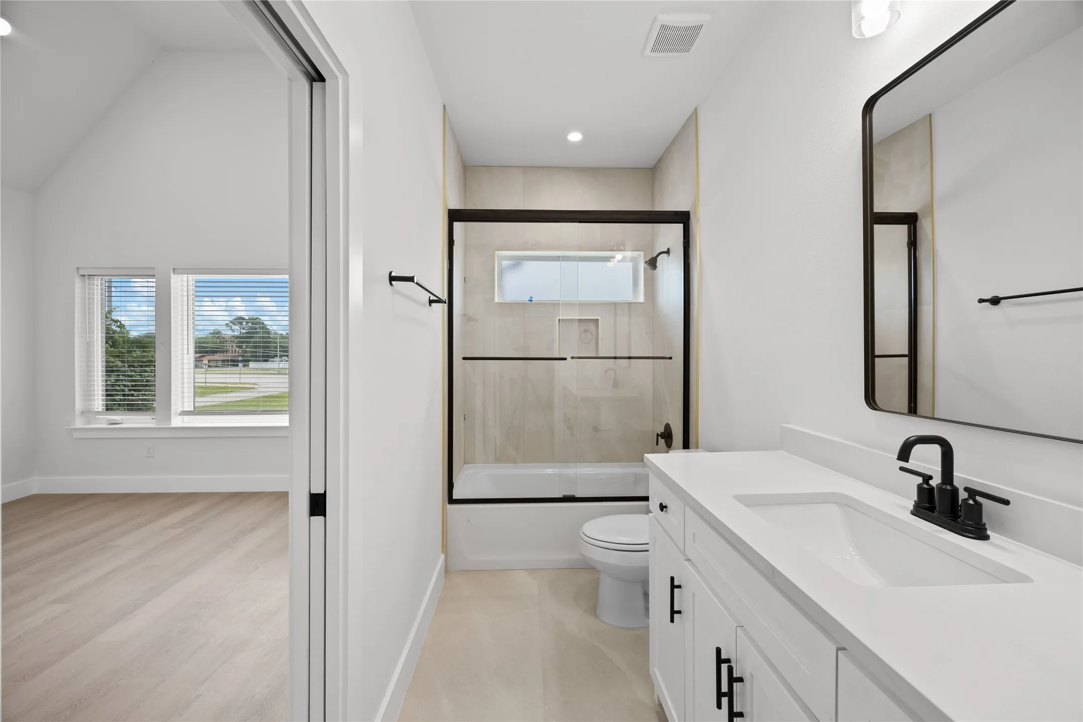 Bathroom featuring a single vanity with a white countertop and integrated sink, matte black faucet, and a rectangular mirror