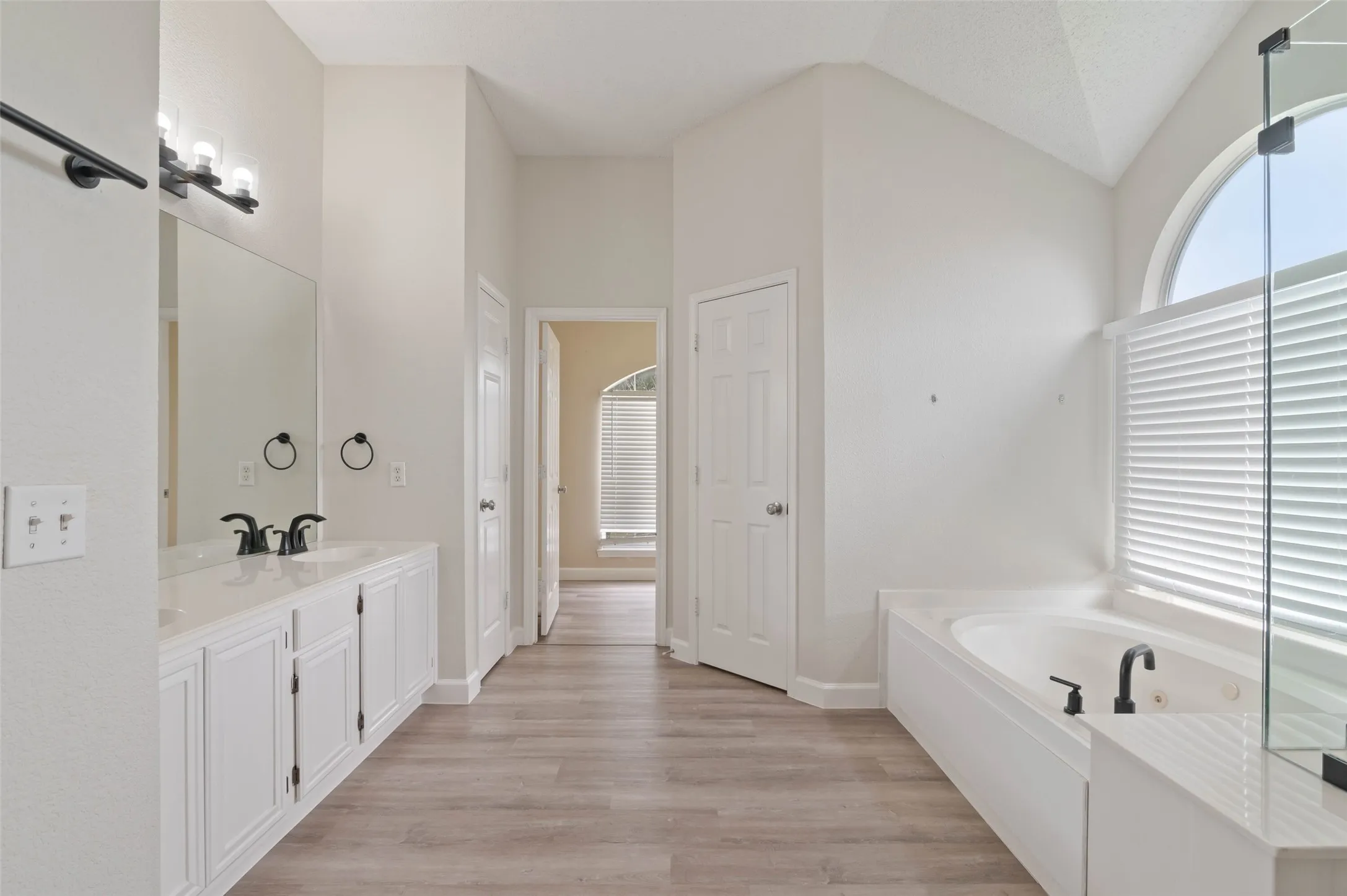 Spacious primary bathroom with dual sinks, separate tub and shower and large walk in closet