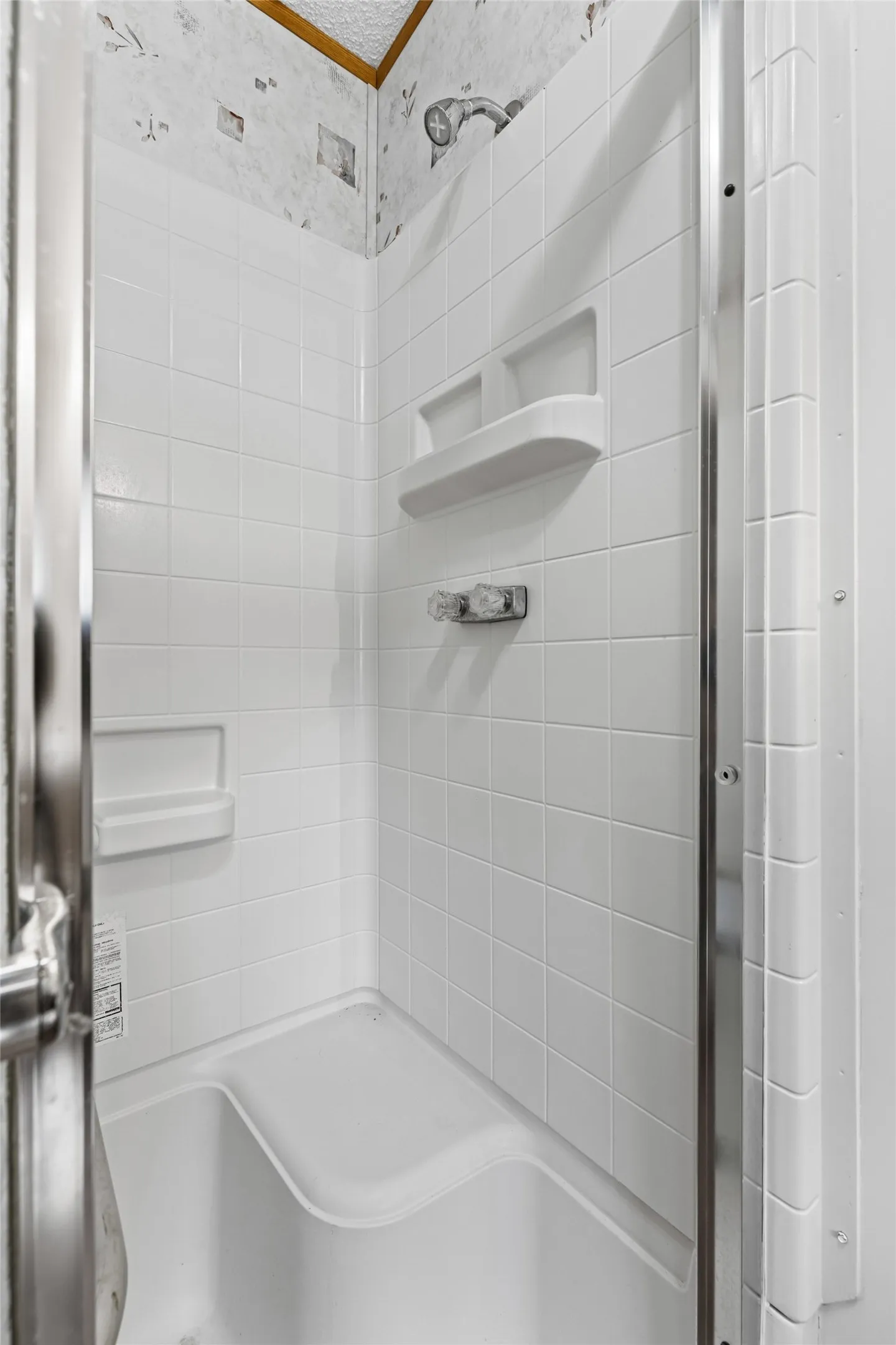 White tiled shower enclosure with integrated shelving and a built-in seat