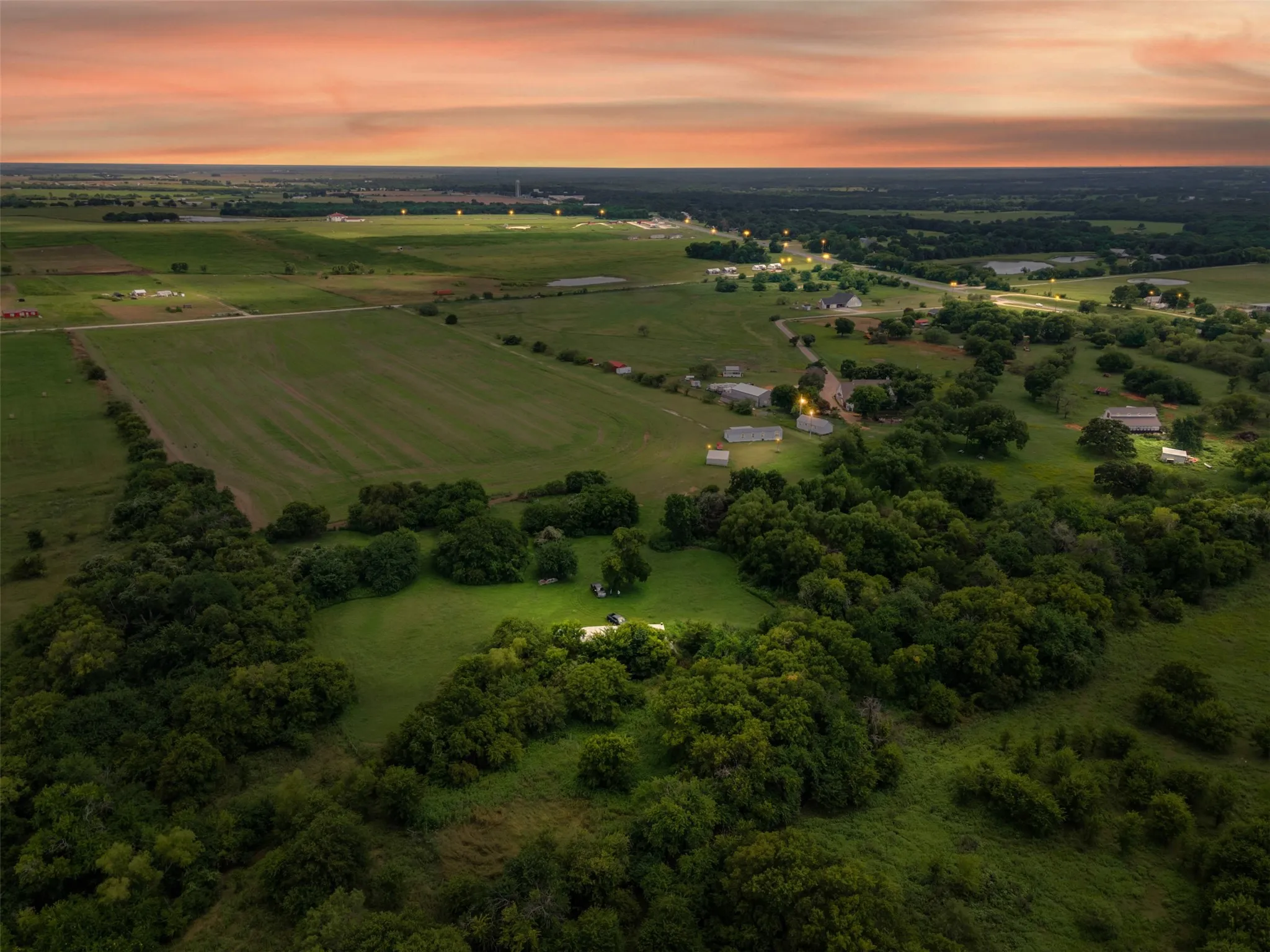 Expansive rural landscape featuring wooded areas, open fields, and scattered residential structures