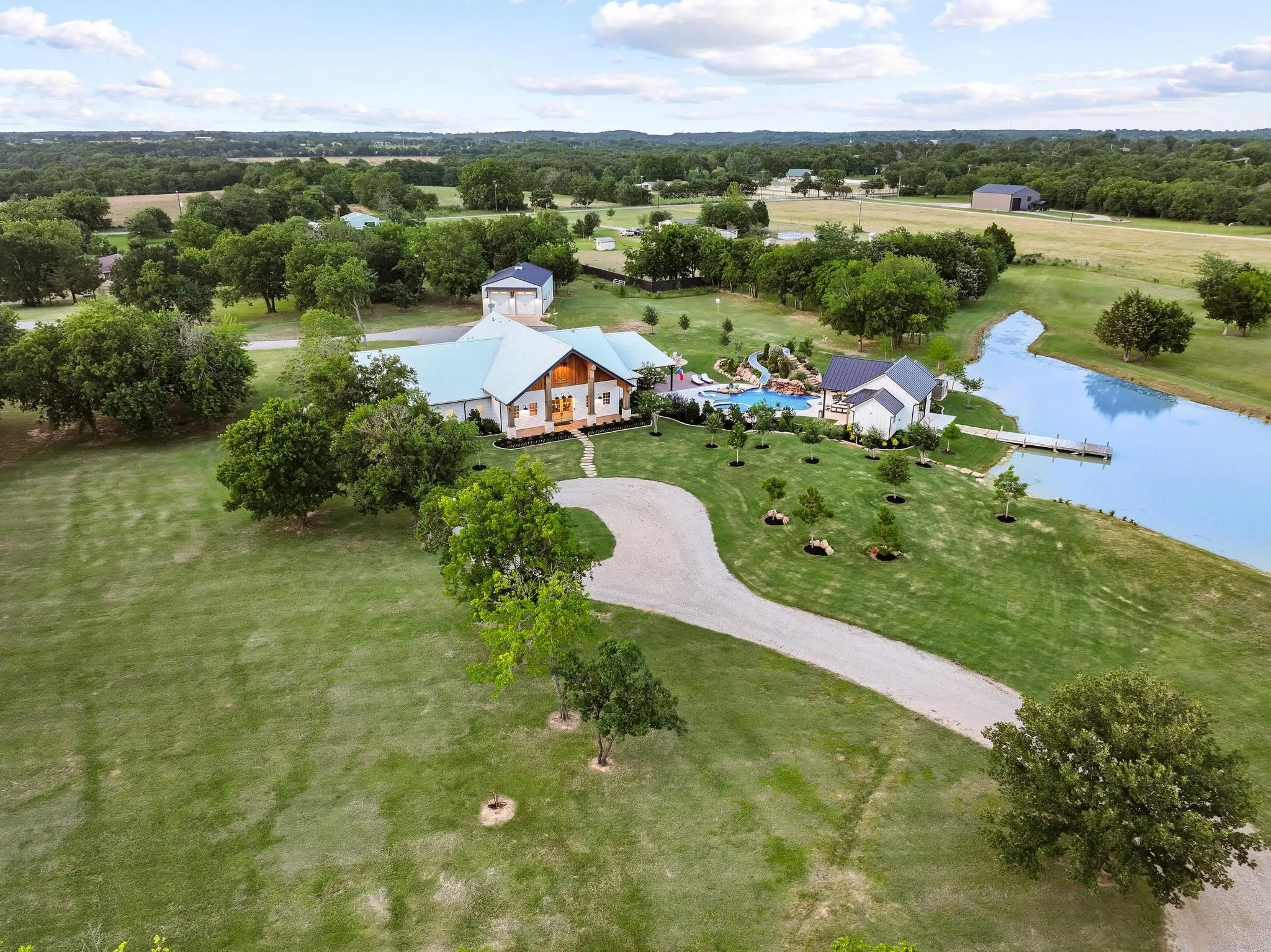 6000+ SF barndominium with circle driveway and stocked pond.