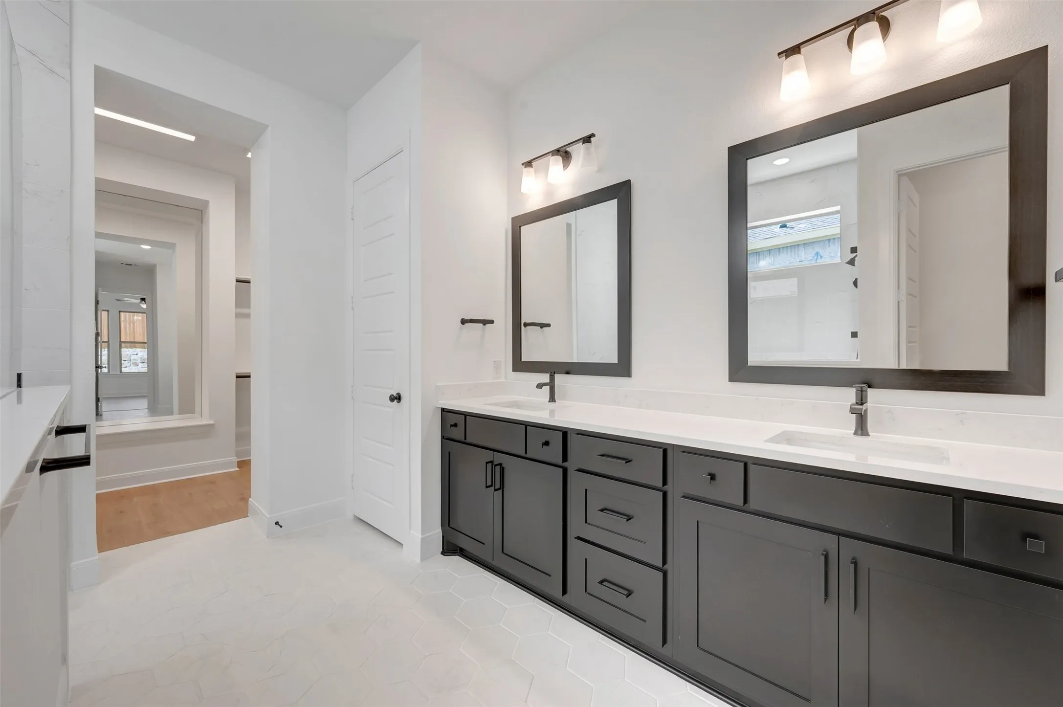 Dual vanity featuring dark cabinetry, white countertops, rectangular sinks, and dark-framed mirrors