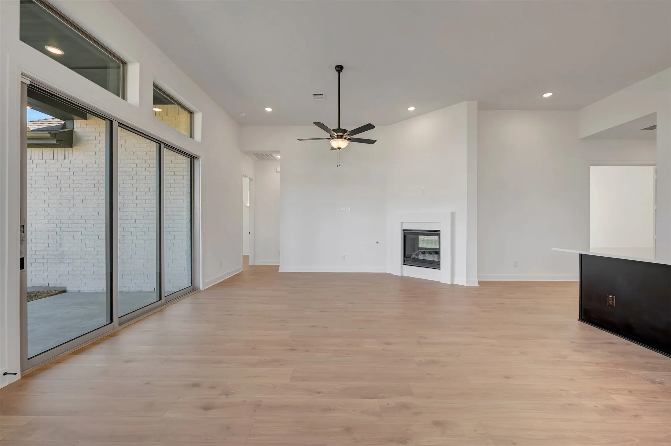 Expansive interior with light wood-finish flooring, a contemporary fireplace, and a ceiling fan