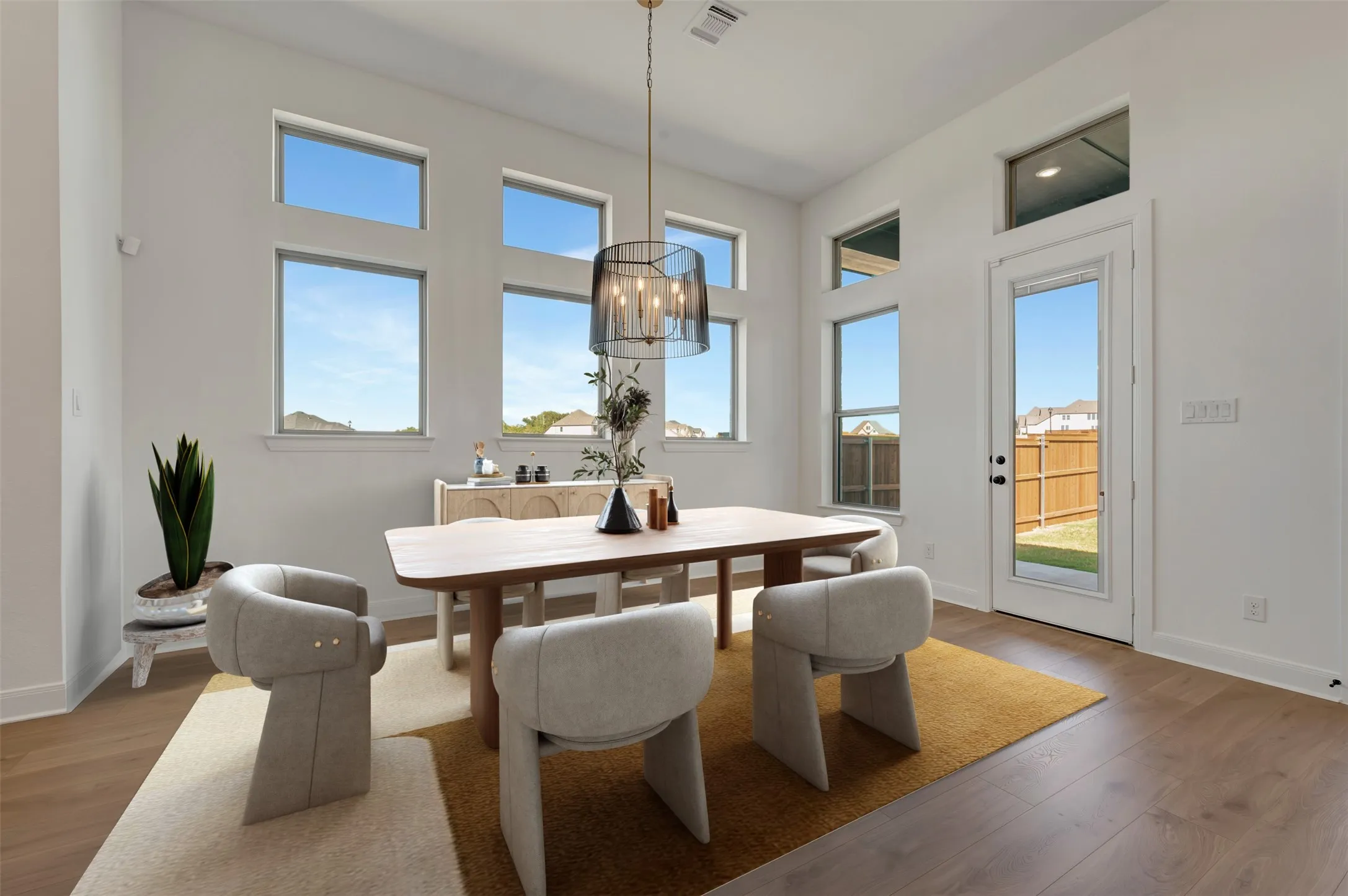 High ceilings, wood-finish flooring, multiple transom windows, full-light door, and a modern chandelier