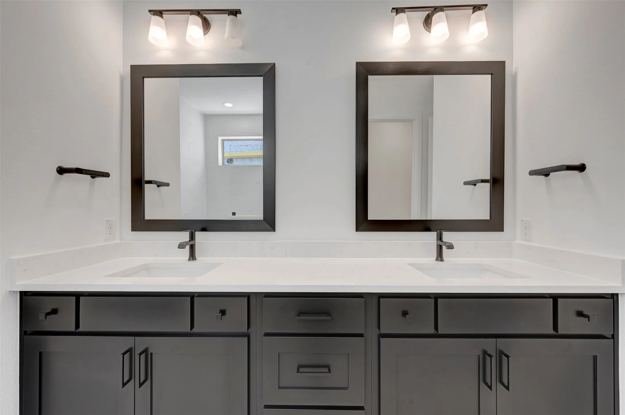 Dual vanity with undermount sinks, white countertop, dark cabinetry, and individual framed mirrors