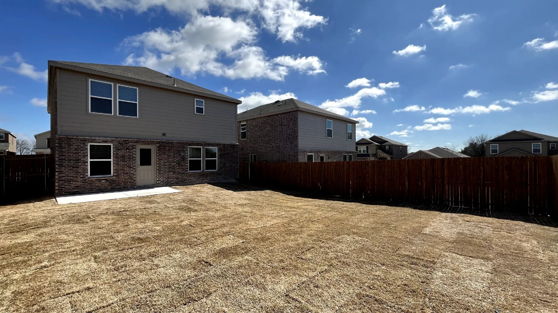 Spacious backyard featuring a new privacy fence, an unlandscaped lawn, and a concrete patio