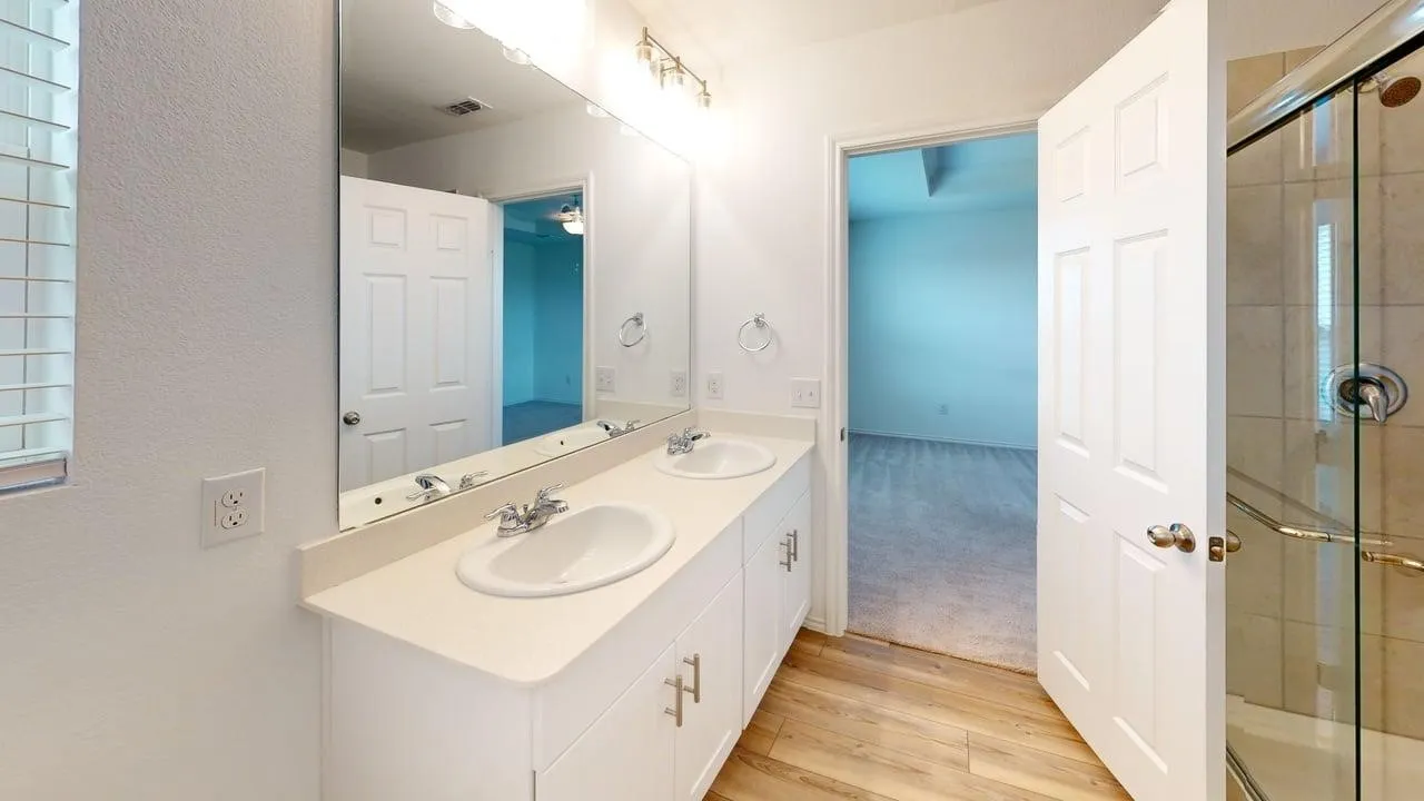 Double vanity with integrated sinks and chrome fixtures, illuminated by a strip light bar