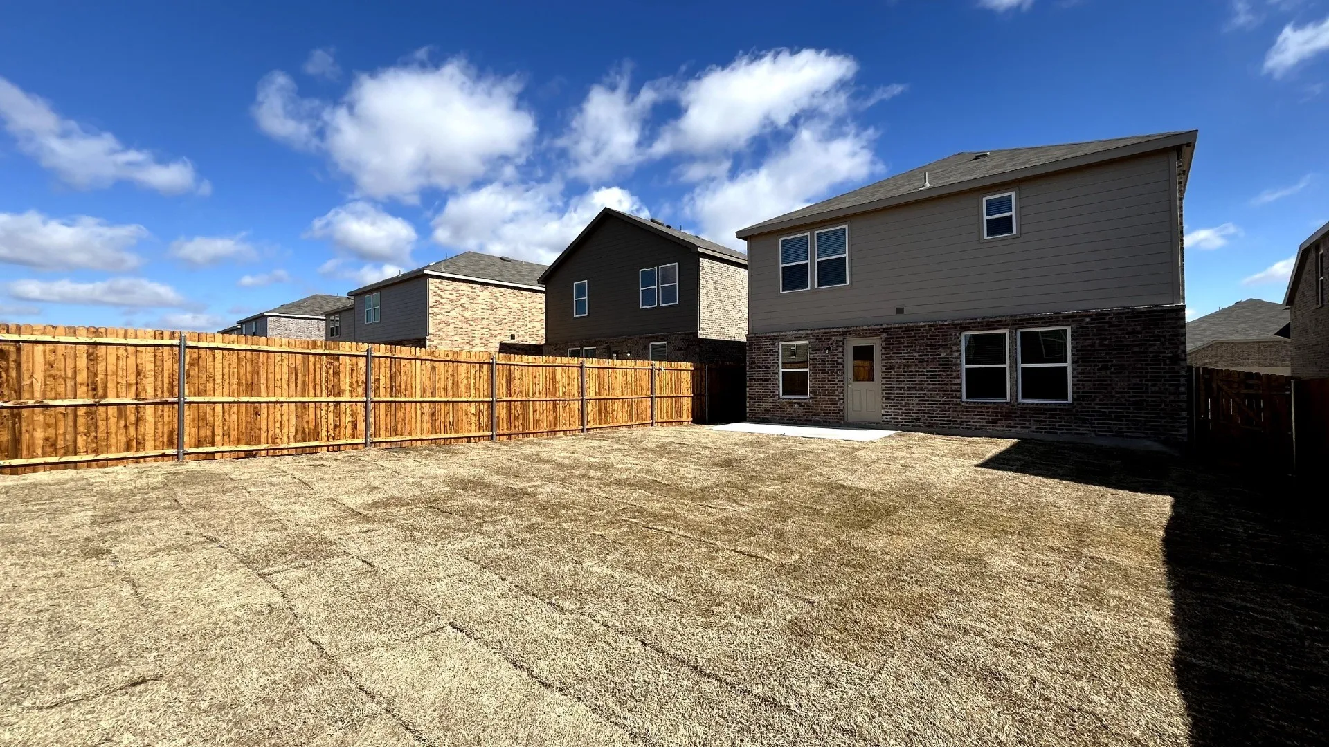 Spacious backyard featuring a newly installed privacy fence, concrete patio, and sod-ready lawn