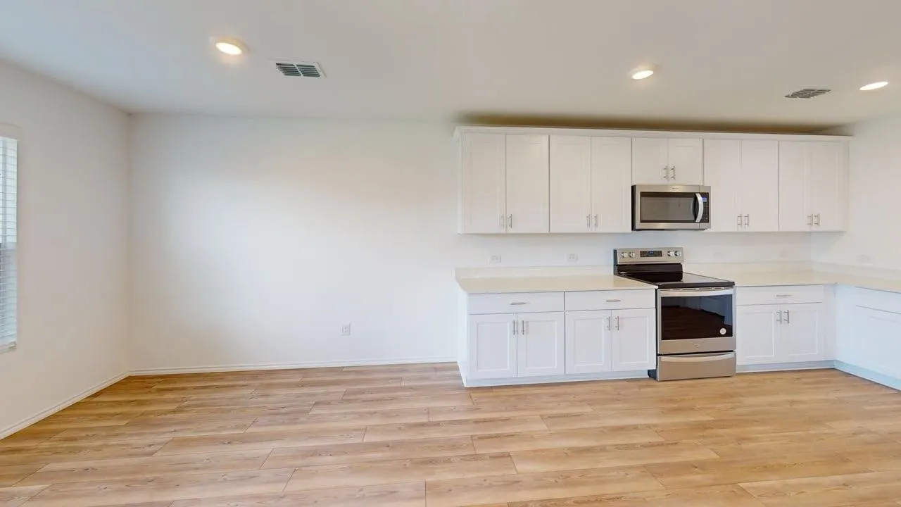 Kitchen featuring white cabinetry, light countertops, stainless steel appliances, and wood-finish flooring