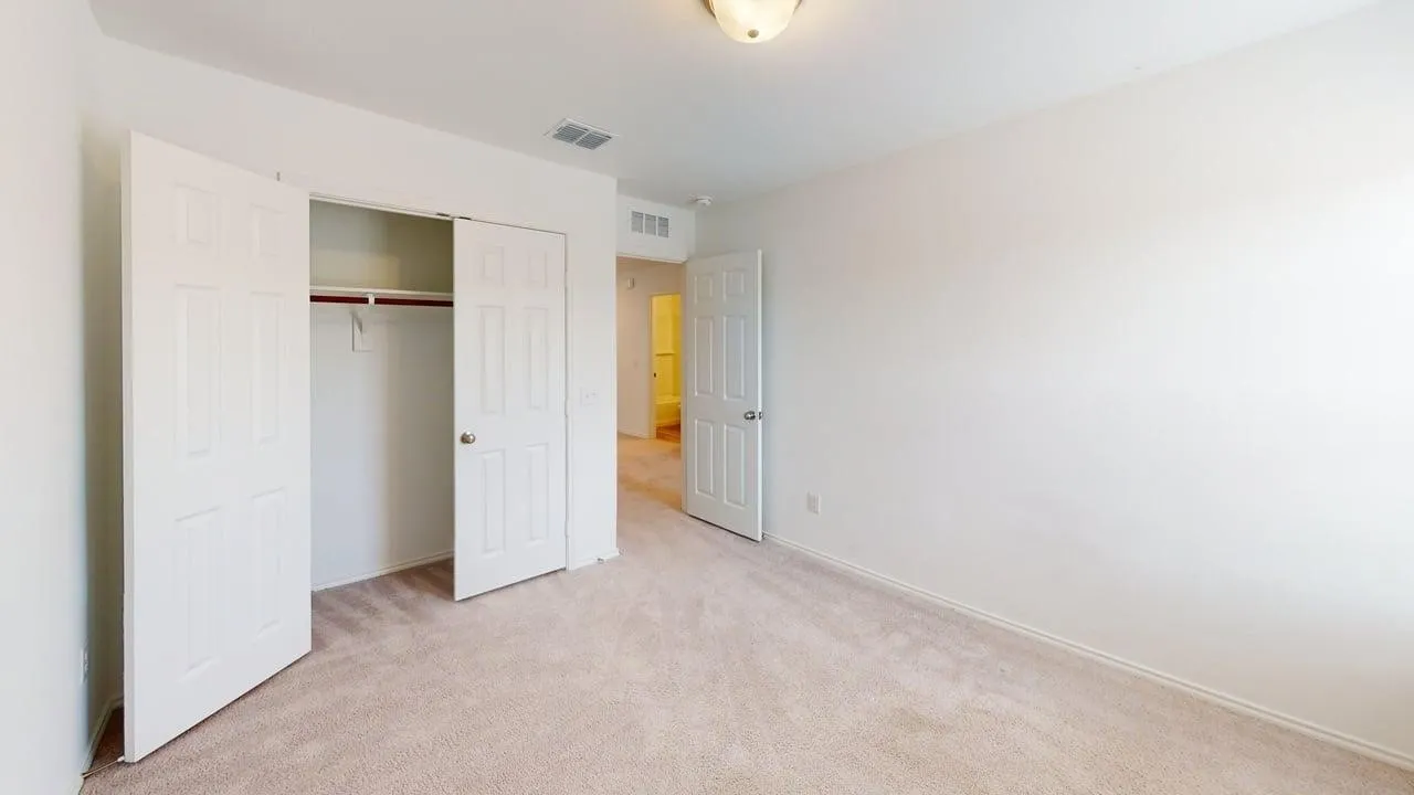 Carpeted room featuring a built-in closet with bi-fold doors and a ceiling-mounted light fixture