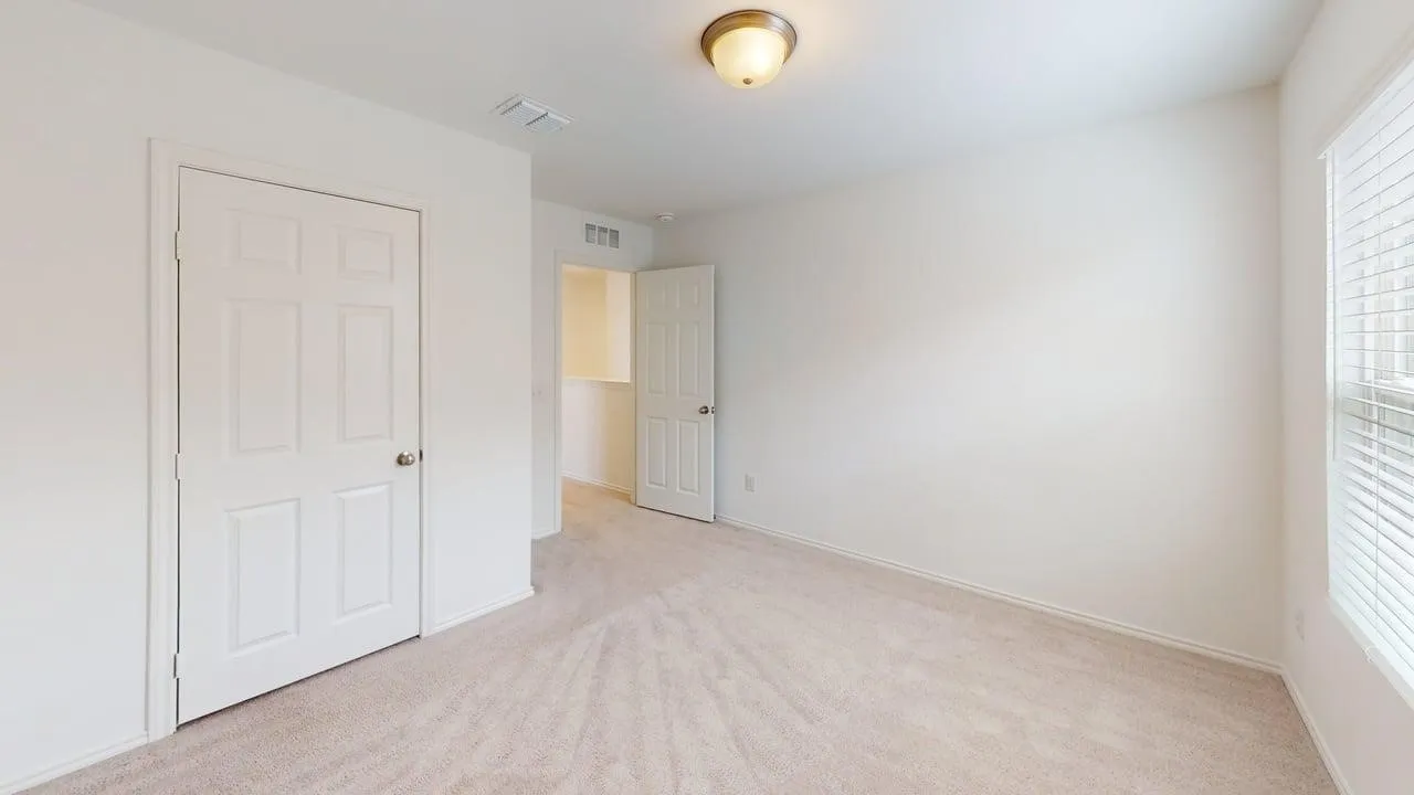 Neutral tone wall finishes, light carpeting, window with blinds, and a six-panel door