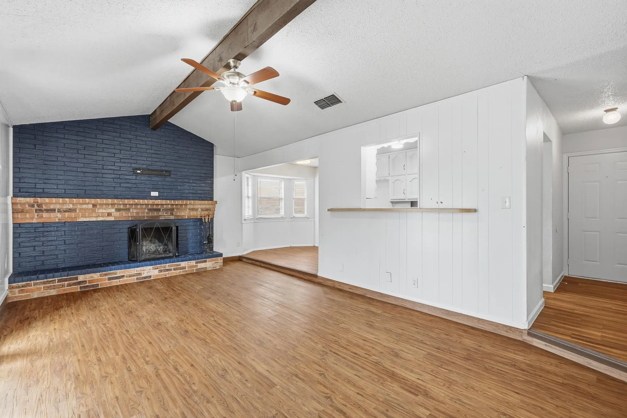 Inviting family room with soaring ceilings, rich wood-look flooring, and a beautiful brick fireplace perfect for gathering with family and friends.