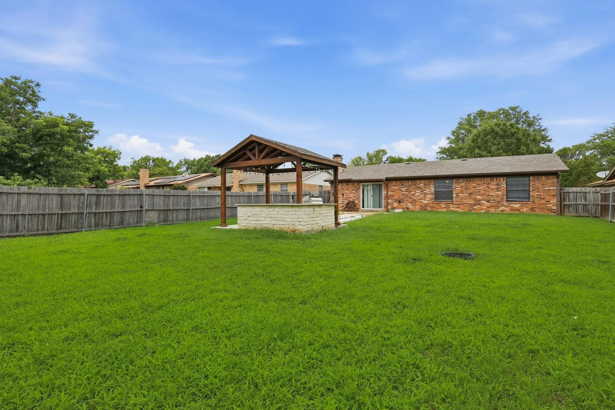 Resort-inspired backyard retreat with a custom timber-frame pavilion, outdoor kitchen, built-in grill, and expansive entertaining space.