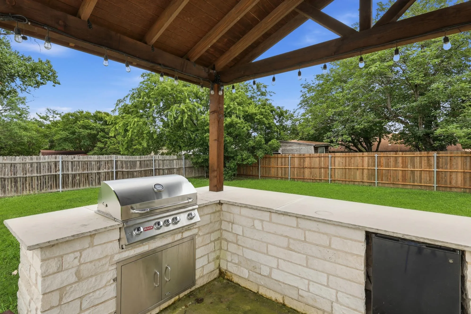 Spacious covered outdoor kitchen and entertainment area overlooking the large fenced backyard.
