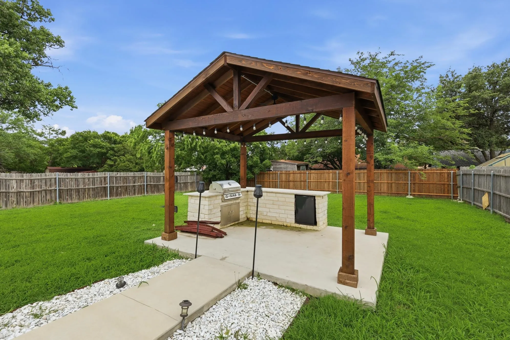 Custom covered outdoor pavilion featuring a built-in grill, refrigerator, serving bar, and ample space for entertaining.
