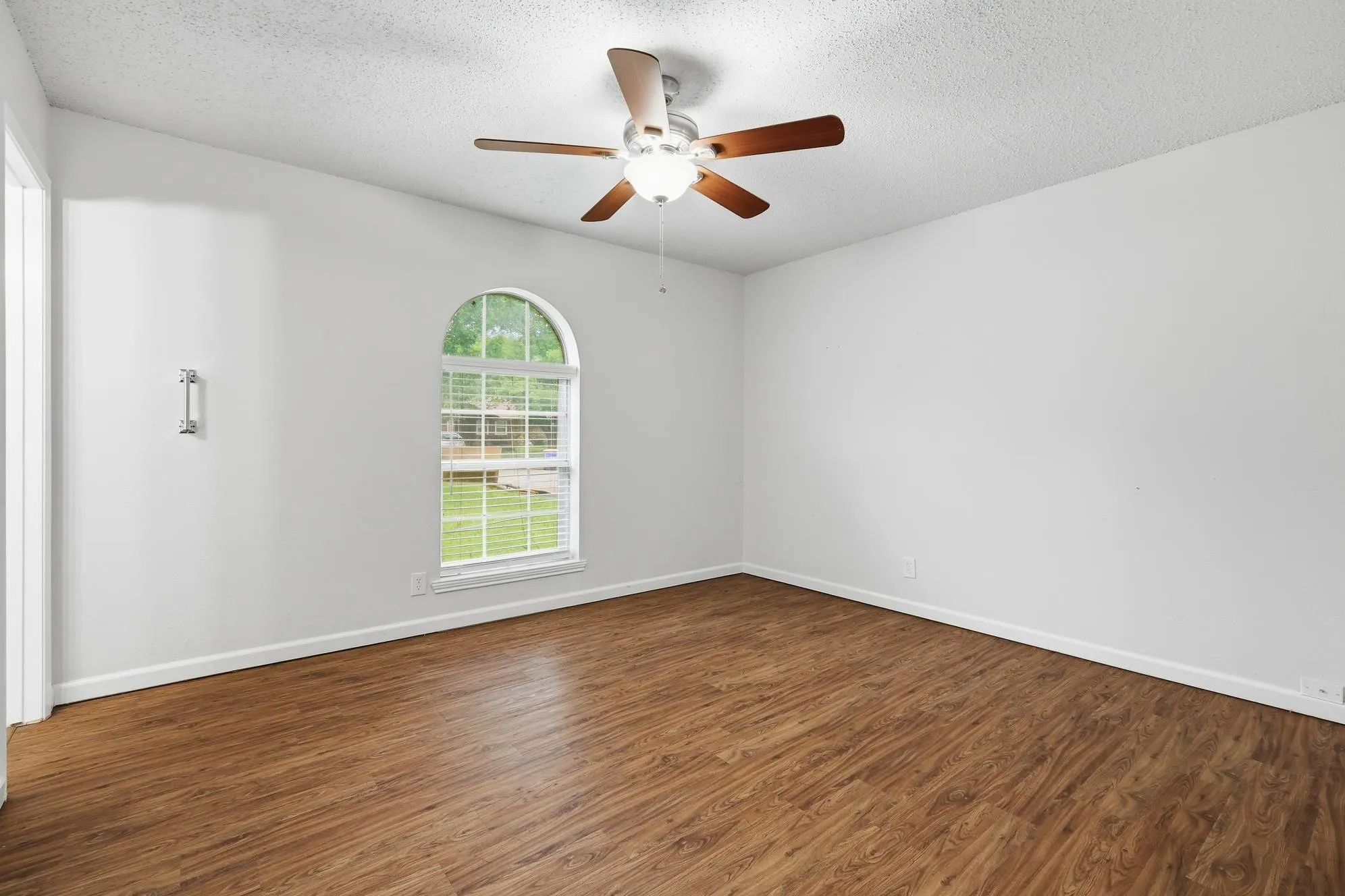 Spacious secondary bedroom featuring durable wood-look flooring, abundant natural light, and a neutral color palette ready for your personal touch.
