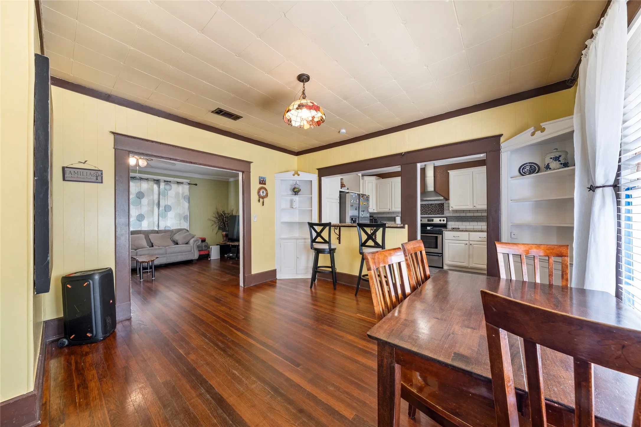Hardwood flooring, built-in shelving, kitchen with stainless steel appliances, recessed lighting, and a decorative ceiling light fixture