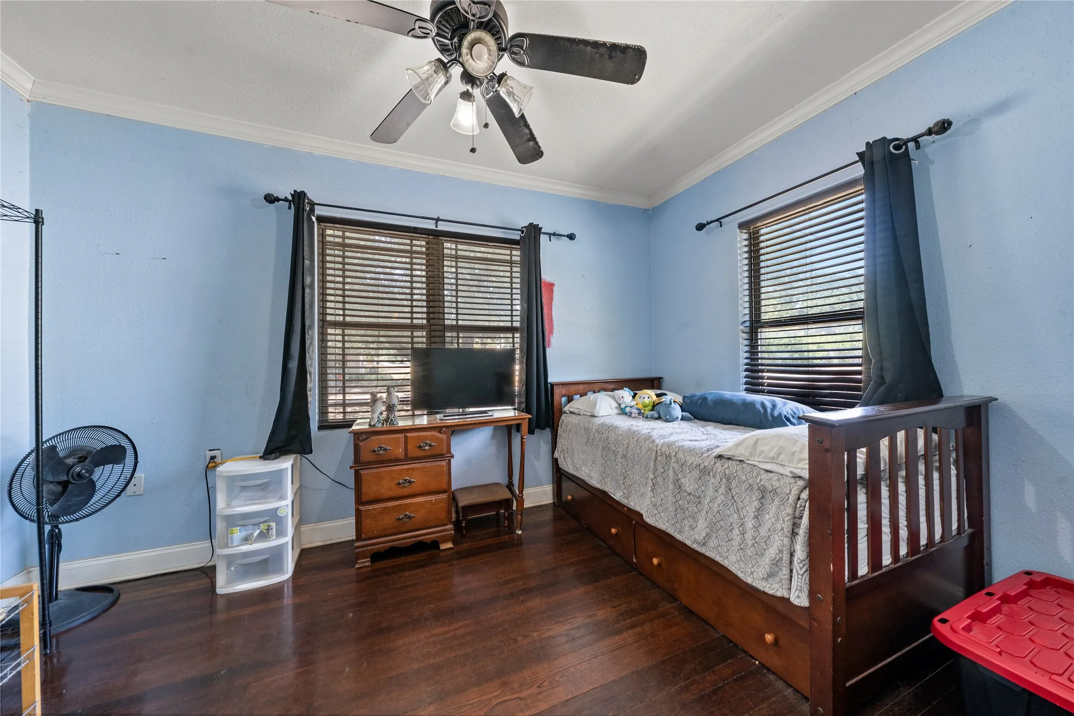 Wood-finish flooring, ceiling fan with light fixture, window with blinds, and white crown molding