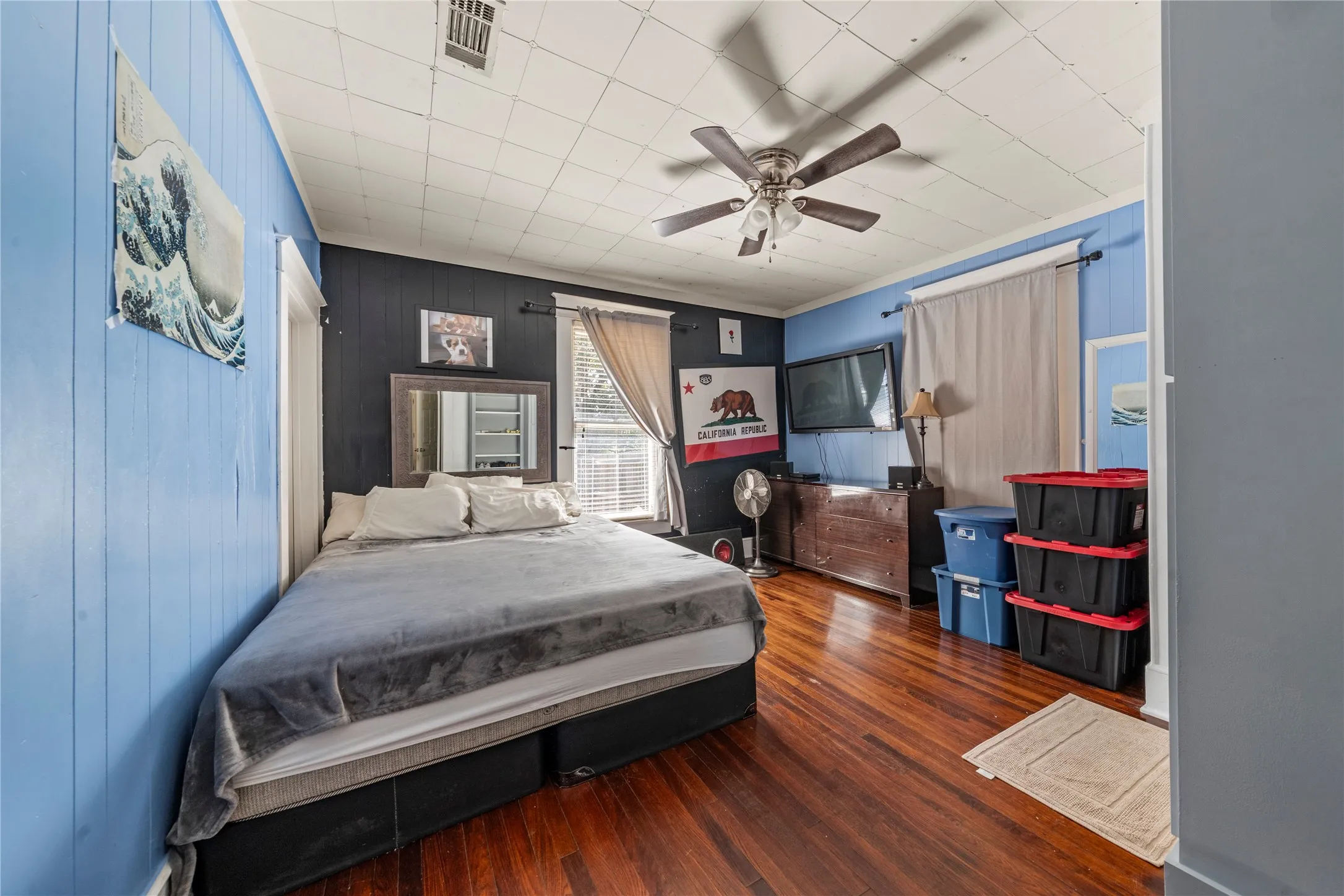 Wood-finish flooring with a ceiling fan and paneled walls