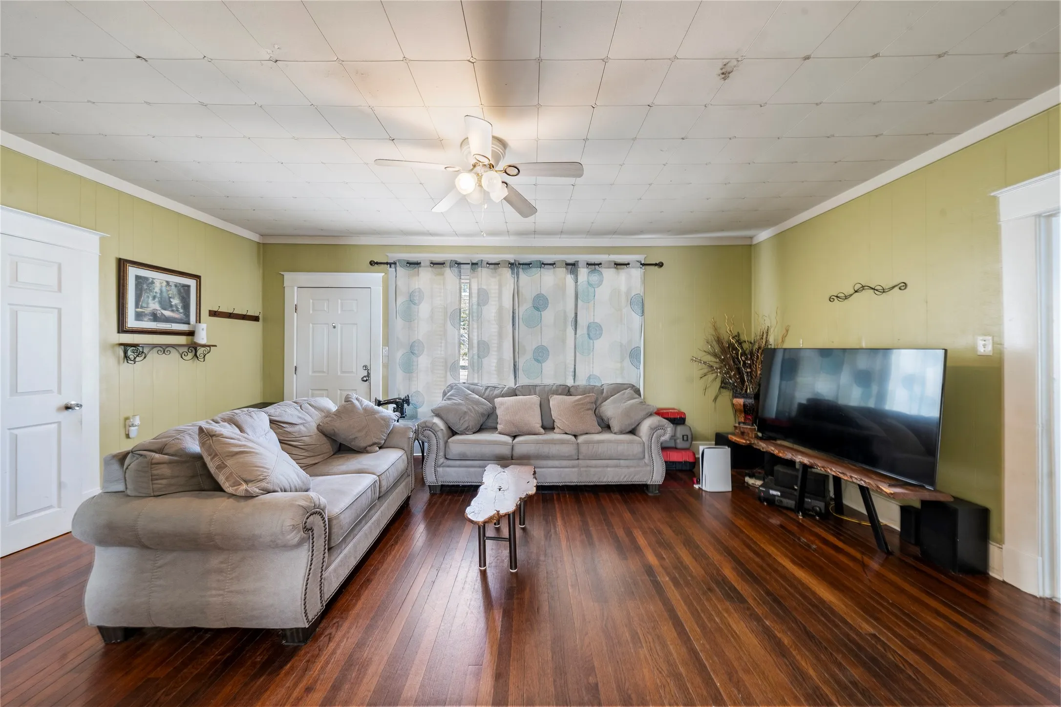 Wood-finish flooring, paneled walls, and a ceiling fan with integrated lighting