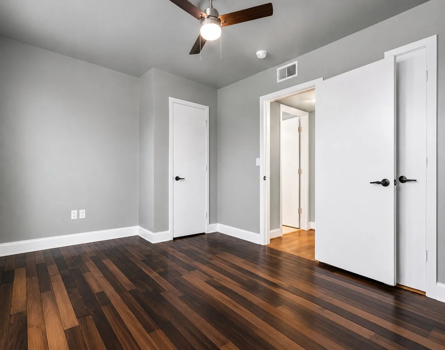 Bedroom featuring wood-finish flooring, light gray walls, and white trim