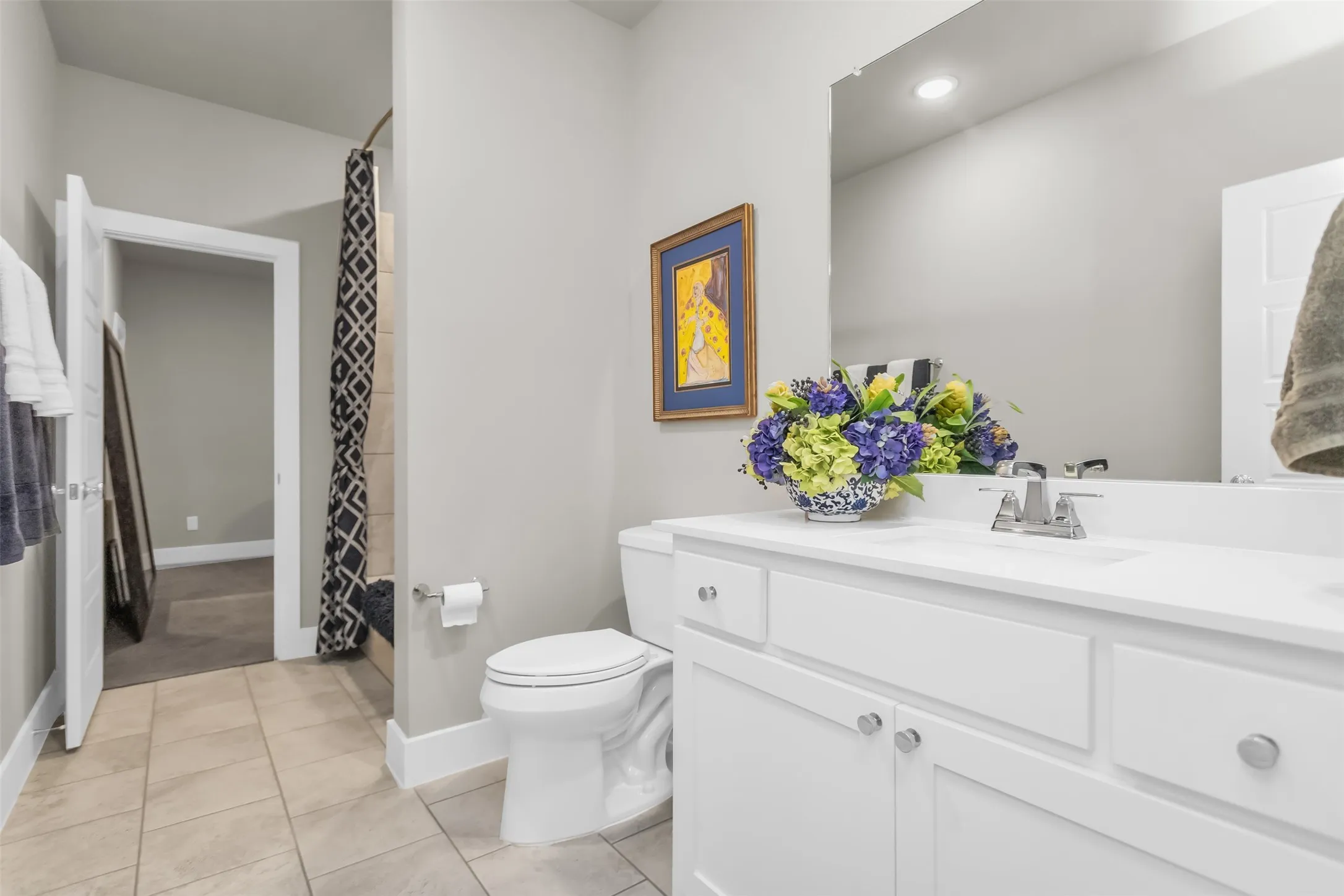 Bathroom with white vanity, single sink, and large wall-mounted mirror