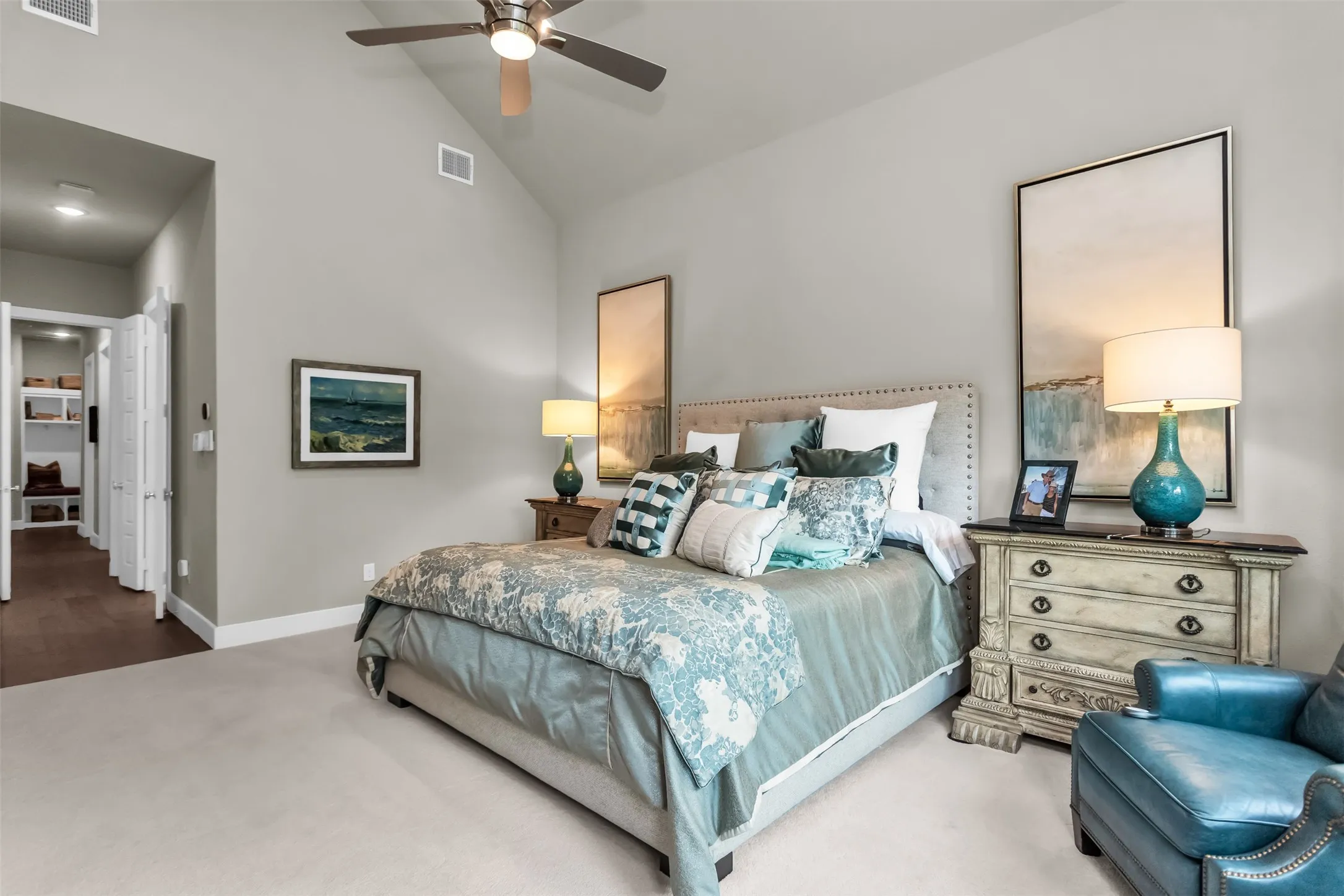 Vaulted ceiling bedroom featuring plush carpet flooring, a ceiling fan with integrated lighting, and a doorway to a walk-in closet with built-in shelving