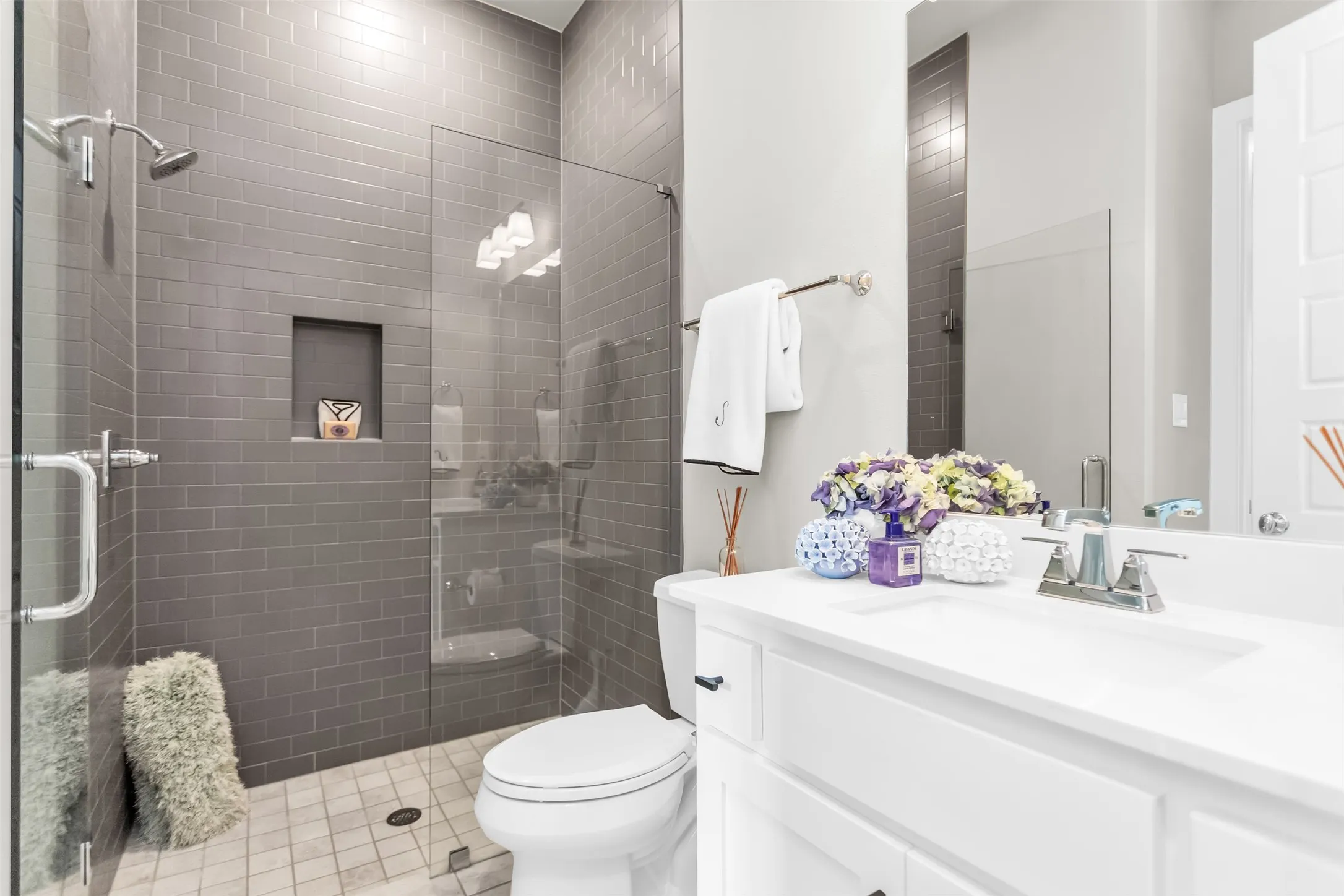 Bathroom featuring a glass-enclosed shower with gray subway tile walls and an integrated shower niche