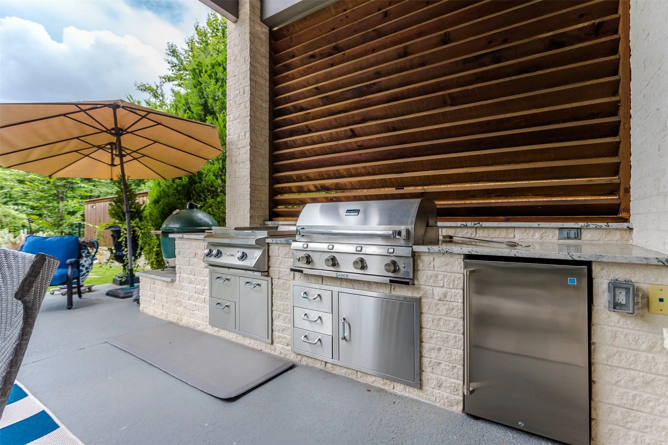 Outdoor kitchen featuring integrated stainless steel appliances, a built-in refrigerator, and stone veneer cabinetry