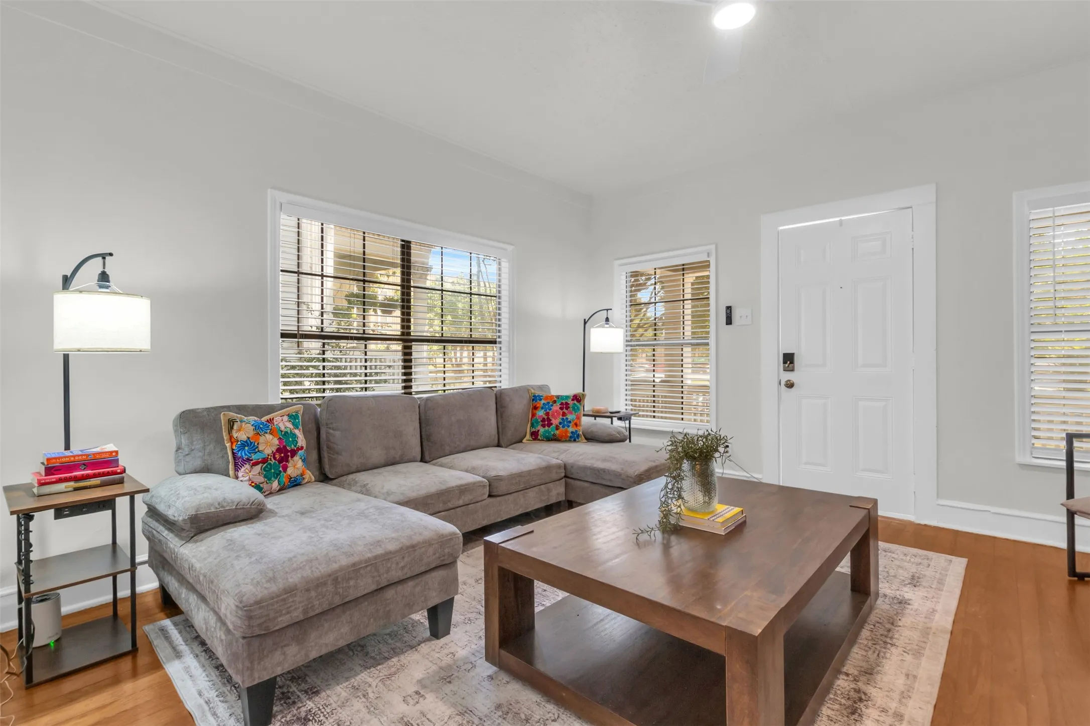 Living area featuring light-toned walls, wood-finish flooring, and white trim